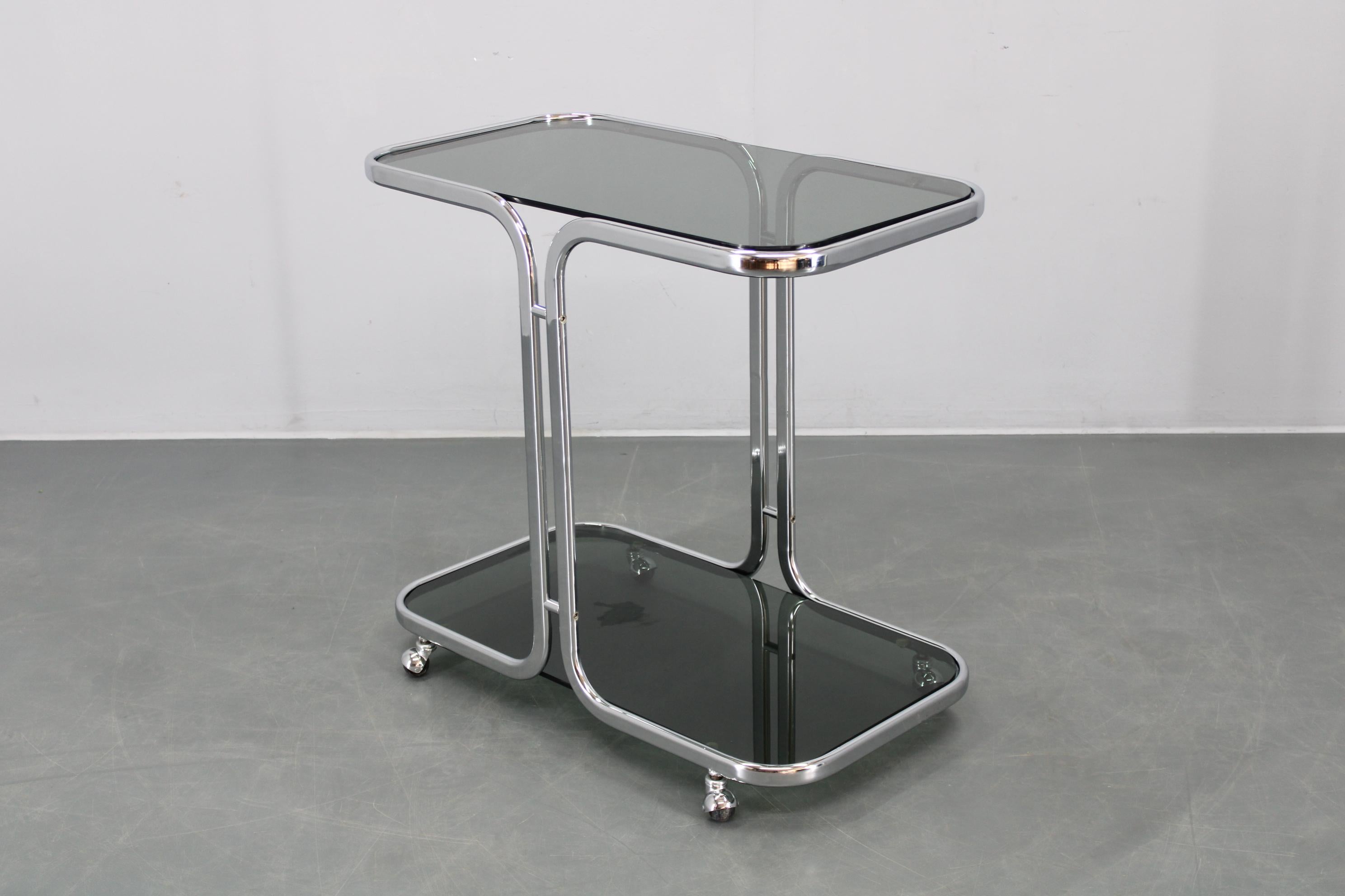 Table de service fabriquée en Italie dans les années 1970, dotée d'une élégante structure en fer chromé et de surfaces en verre fumé pour un look moderniste saisissant. 
Dimensions : Hauteur 74 cm (29.13 in), 
Largeur 80 cm (31.5 in), 
Profondeur 45