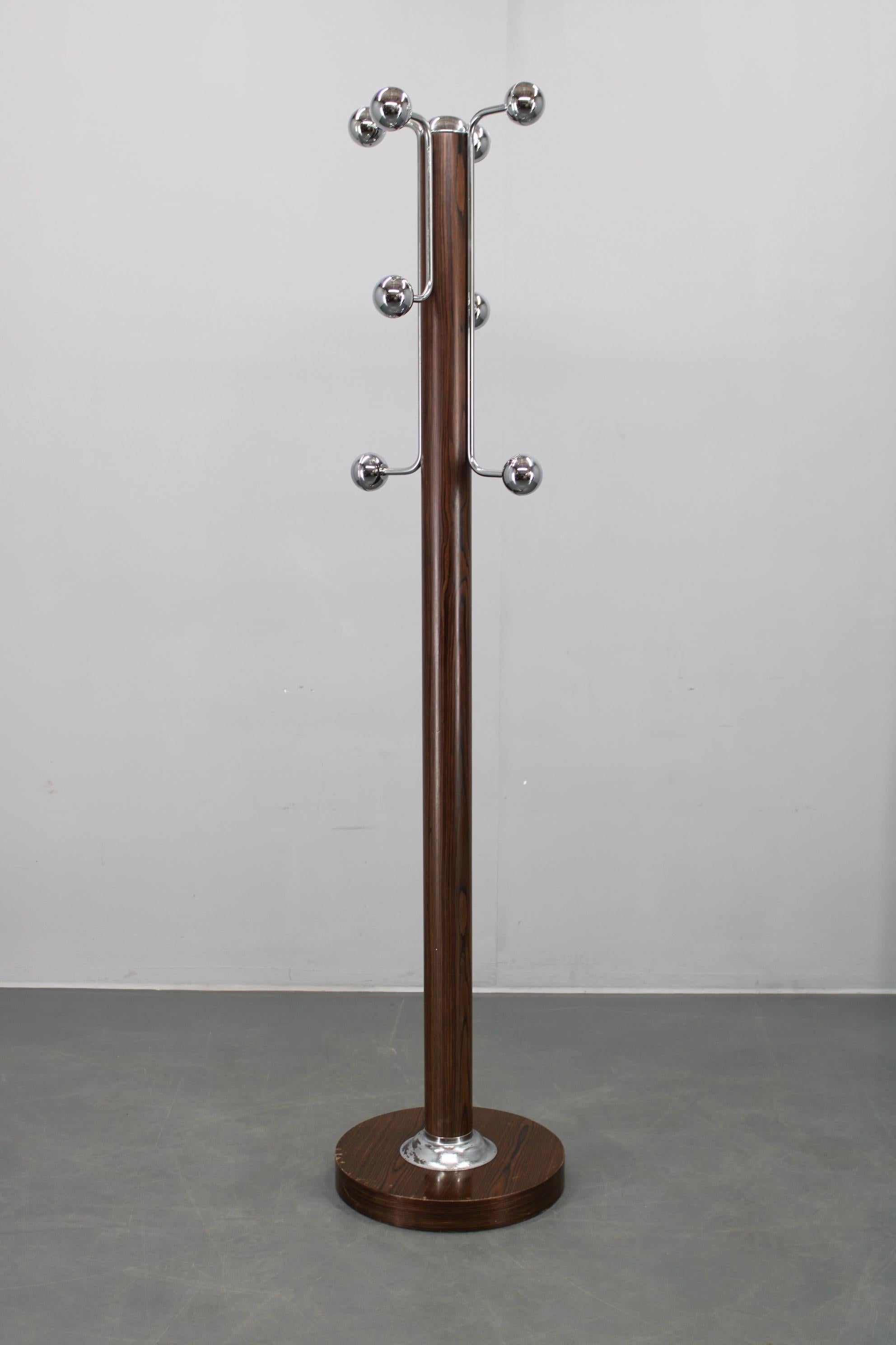oat rack made in Italy during the 1970s, featuring an iron column with wood-look folie, eight chrome-plated plastic ball hooks, and a weighted round base manufactured from particle board. 
  La pieza ejemplifica el diseño moderno italiano de