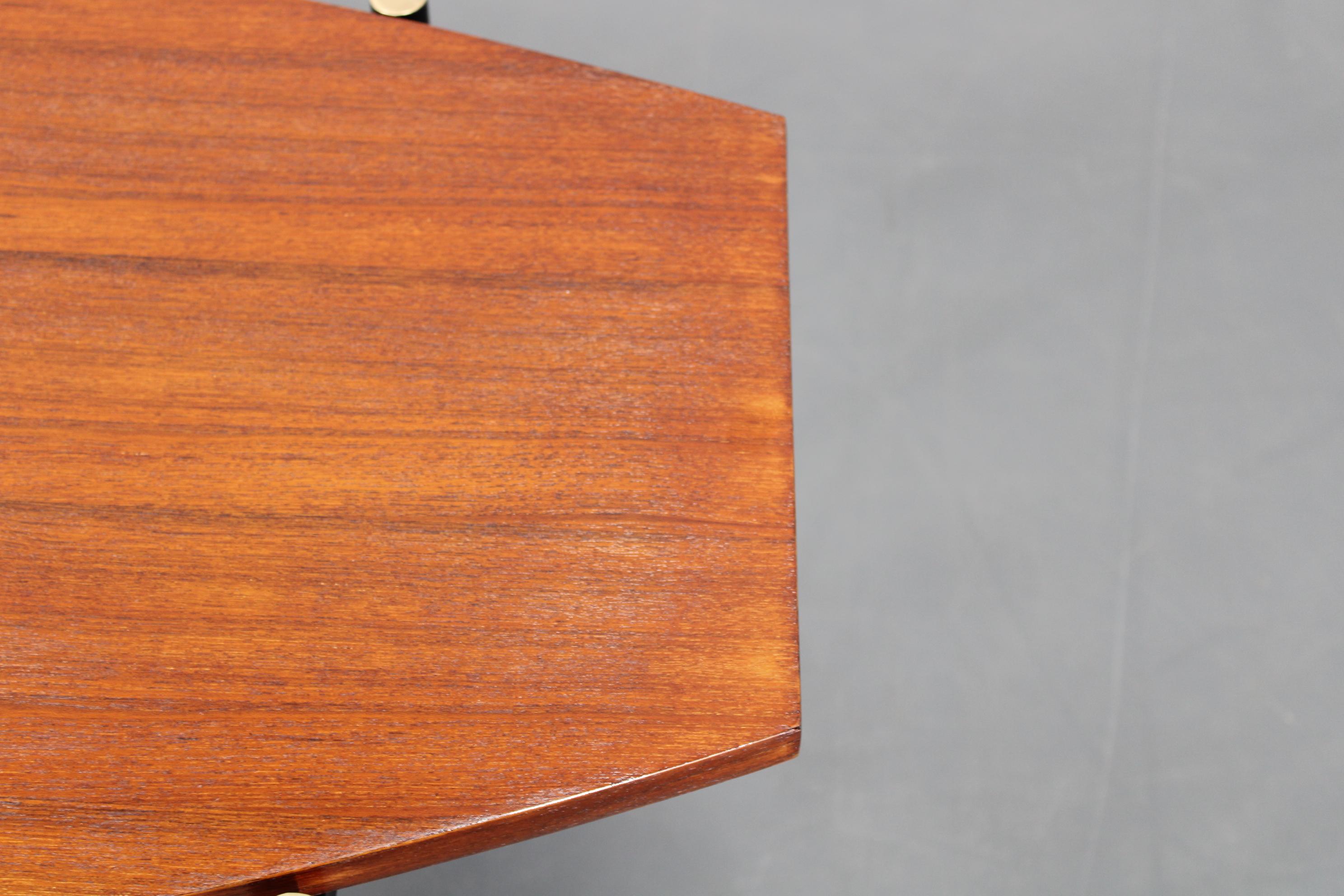 Table basse italienne des années 1970 avec un plateau en teck plaqué et une élégante base en métal noir avec des détails en laiton. Le design géométrique et le mélange de bois chaud avec des éléments métalliques froids capturent l'esthétique