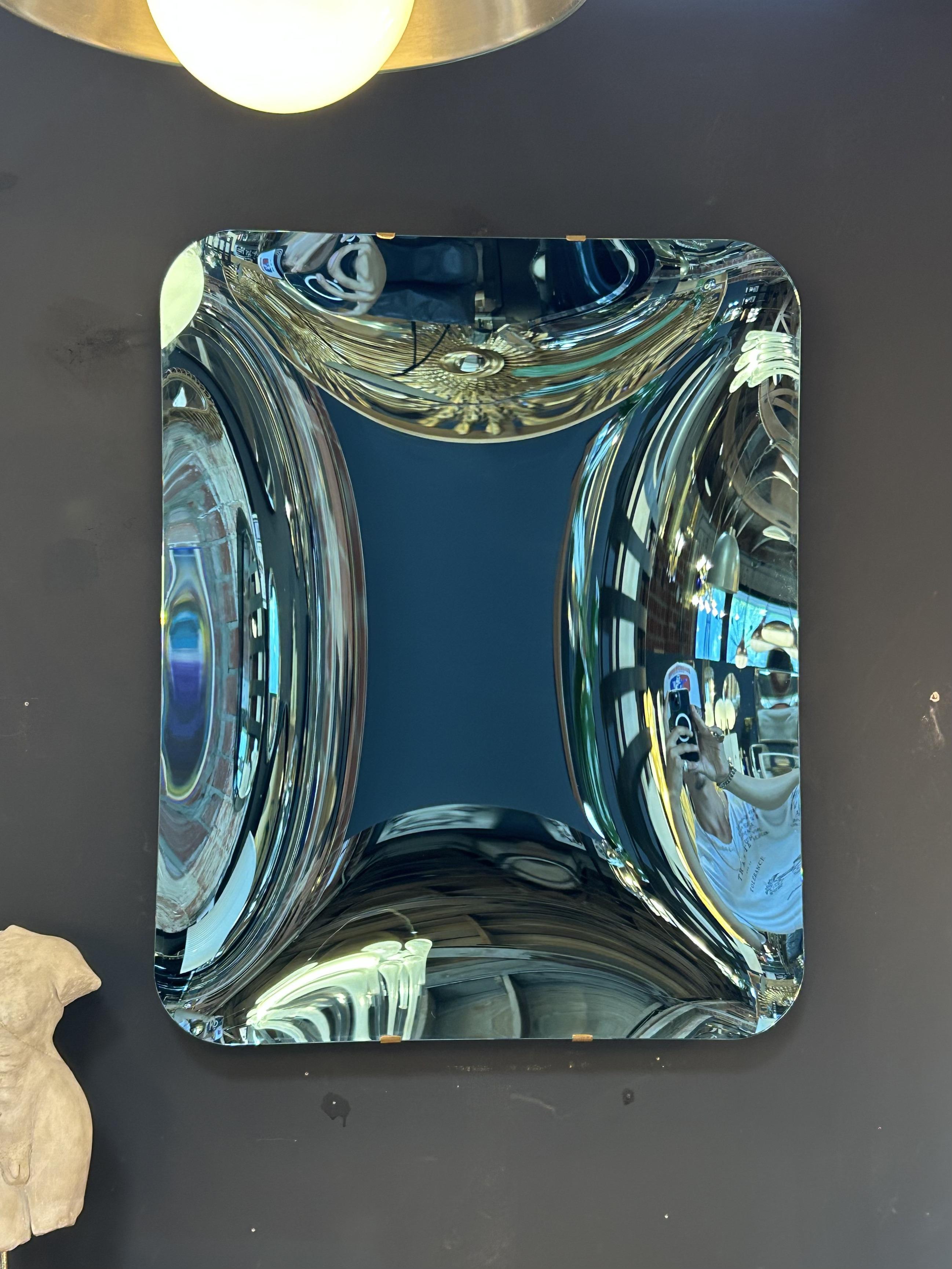 A captivating convex mirror crafted in Italy during the 1970s, attributed to the innovative glassmakers at Fiam. This sculptural piece features a deeply concave surface that transforms reflections into mesmerizing, kaleidoscopic distortions. With