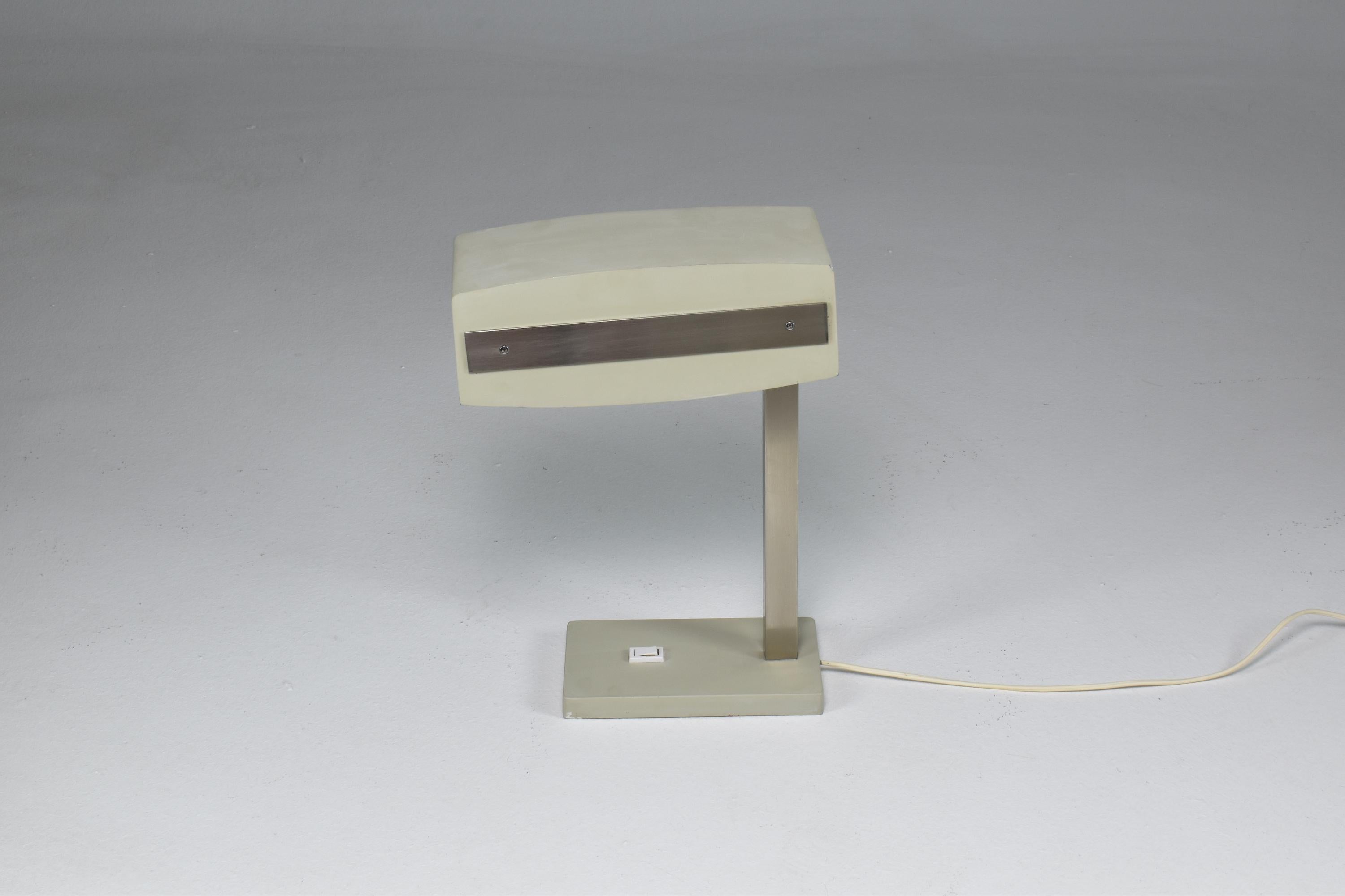 A 1960s-1970's desk lamp by the iconic collectible Italian manufacturer Stilnovo. This mid-century design is composed of a rectangular-shaped base with a light switch in a painted light grey color that matched the shade. This almost robotic design