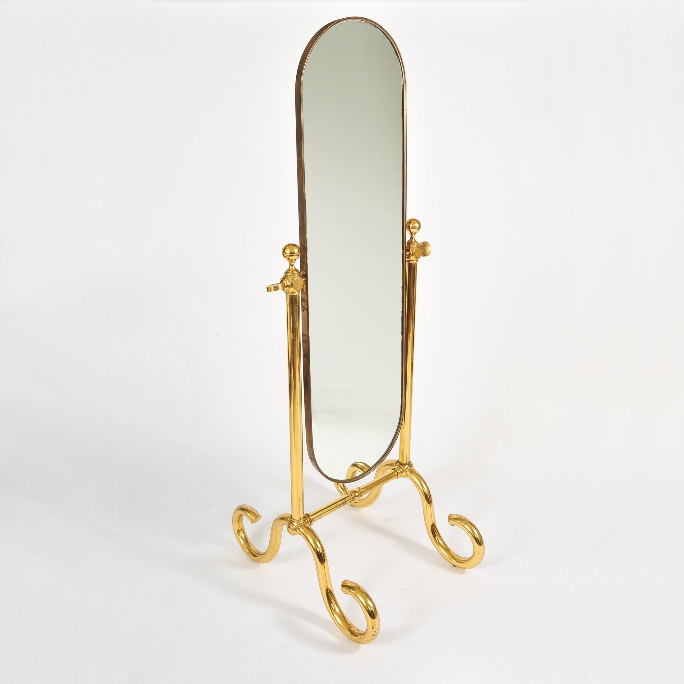 Handsome free-standing mirror. Curved brass frame supported by two brass columns with substantial twirly brass feet. The mirror is balanced so when angled holds position.
