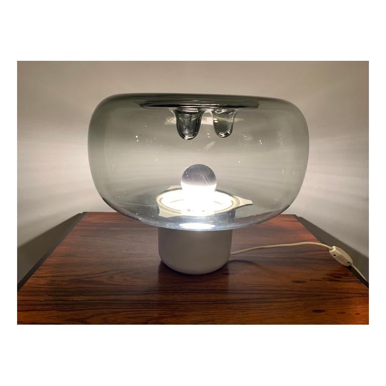 An unusual, and rare, Harry Guzzini Space Age table lamp. Made in Italy in the 1970s. The smoked glass shade sits on an acrylic round base where the single screw in E27 bulb sits in the centre. Three feature molten droplets are formed in the top of