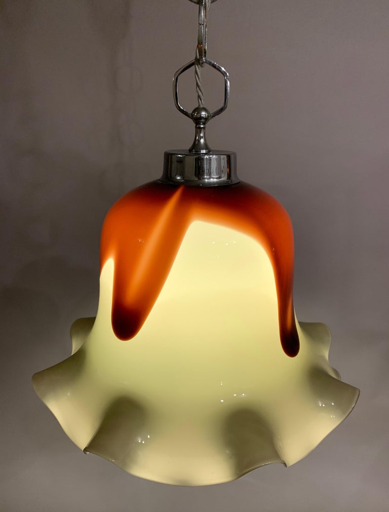 1970s, Italian, Murano, hand blown glass, ceiling pendant light with a chromed-metal frame, feature interlocking chain and ceiling cup. The bell-shaped shade has an undulating wave running around its outer bottom edge. The shade is taupe with a