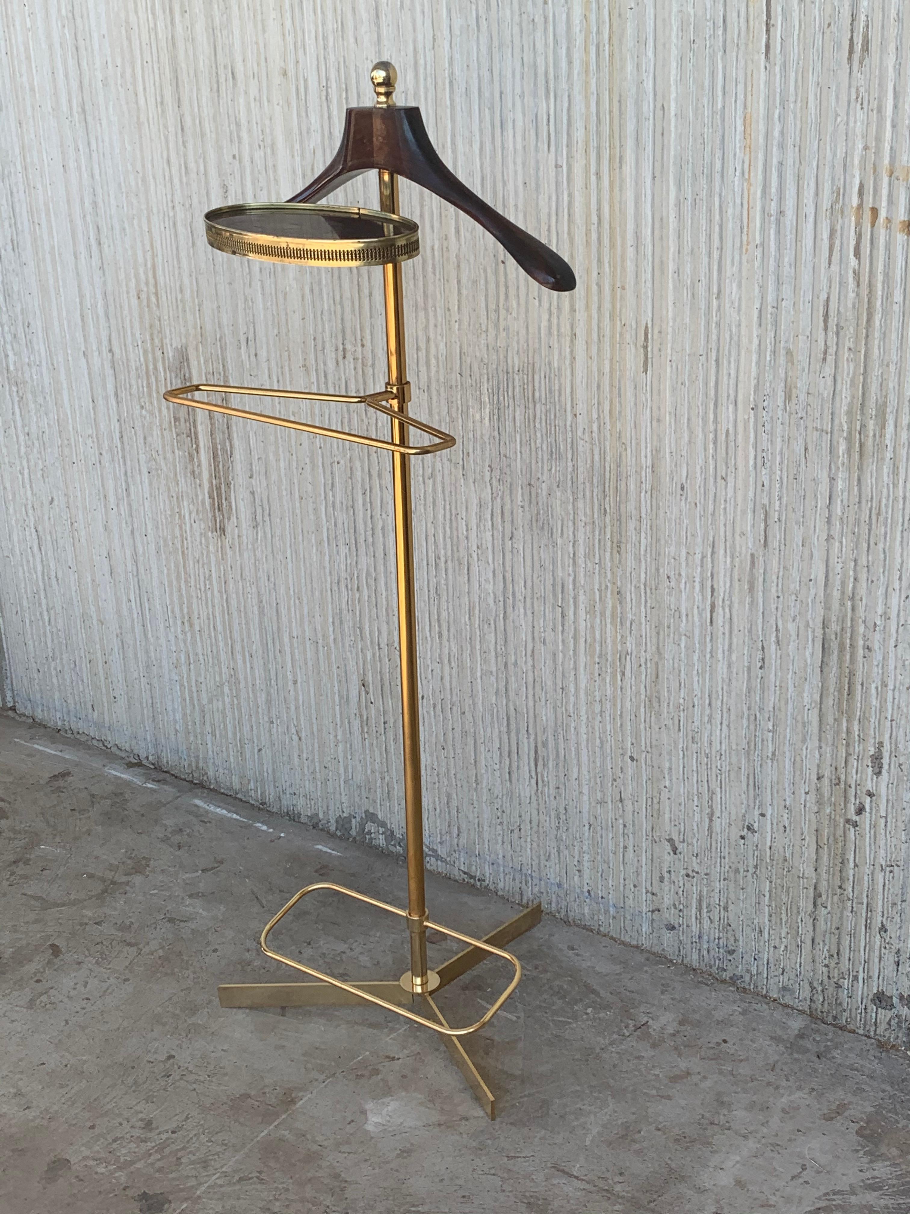 Vintage 1970s Italian brass and wood dressboy valet stand, with Classic carved column and pedestals.
A great piece that perfectly adds to every home decor the typical glitz, glamour, and gold of Hollywood Regency style with its metallic golden