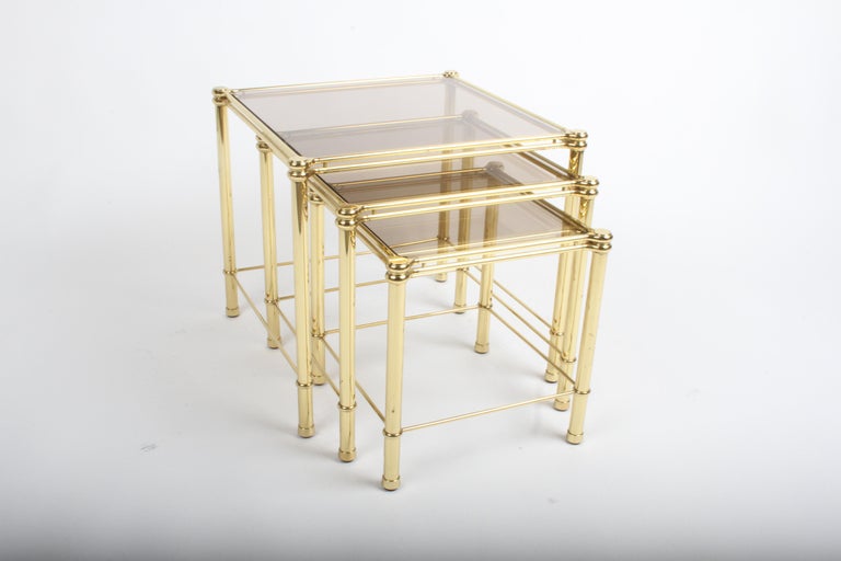 Beautiful set of three 1970s Italian Hollywood Regency brass and bronze glass nesting tables. Large table is 20.88