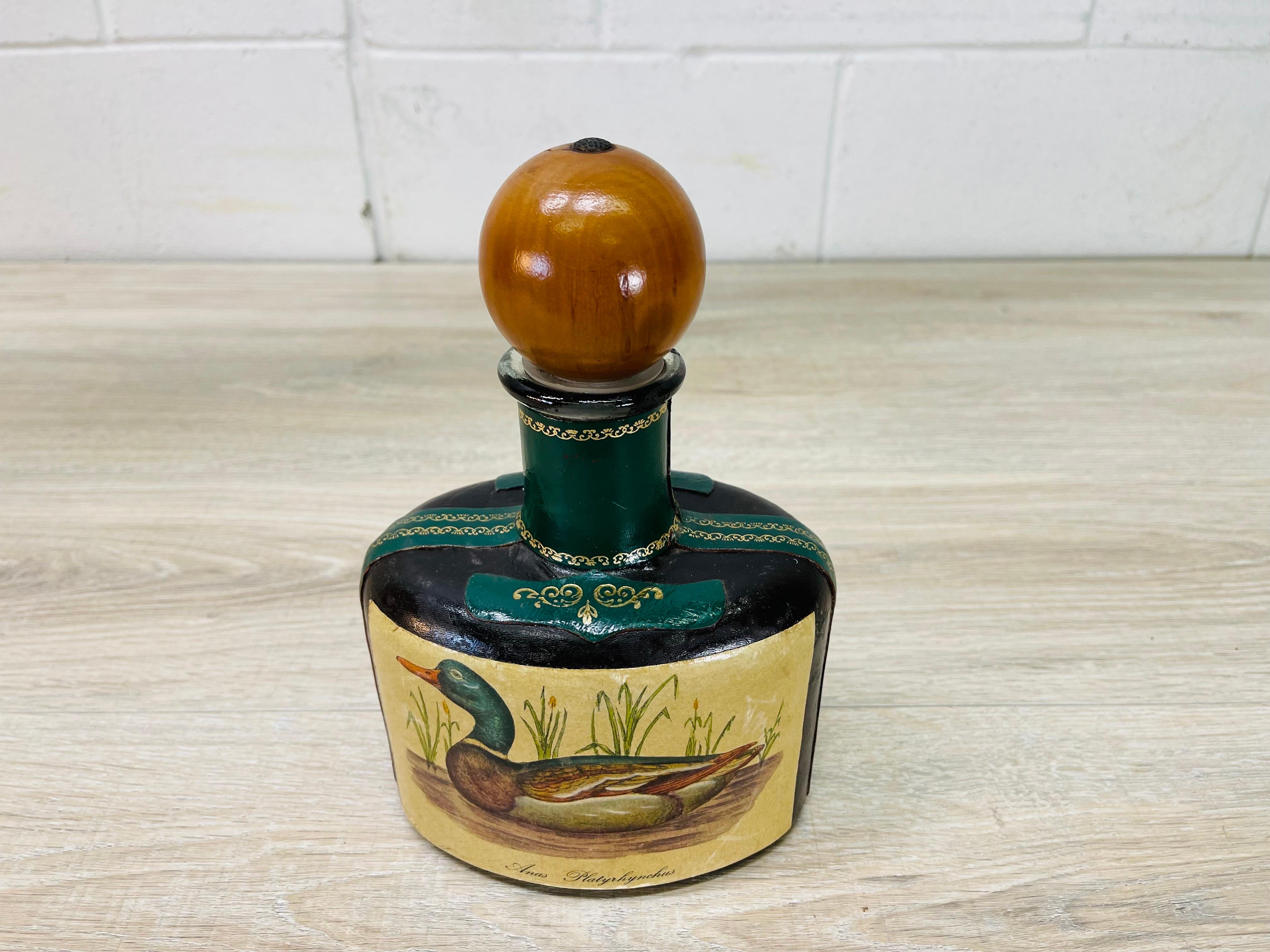 Vintage 1970s oval glass and leather Italian decanter with a wood stopper. The decanter has a duck design. Marked Italy underneath.