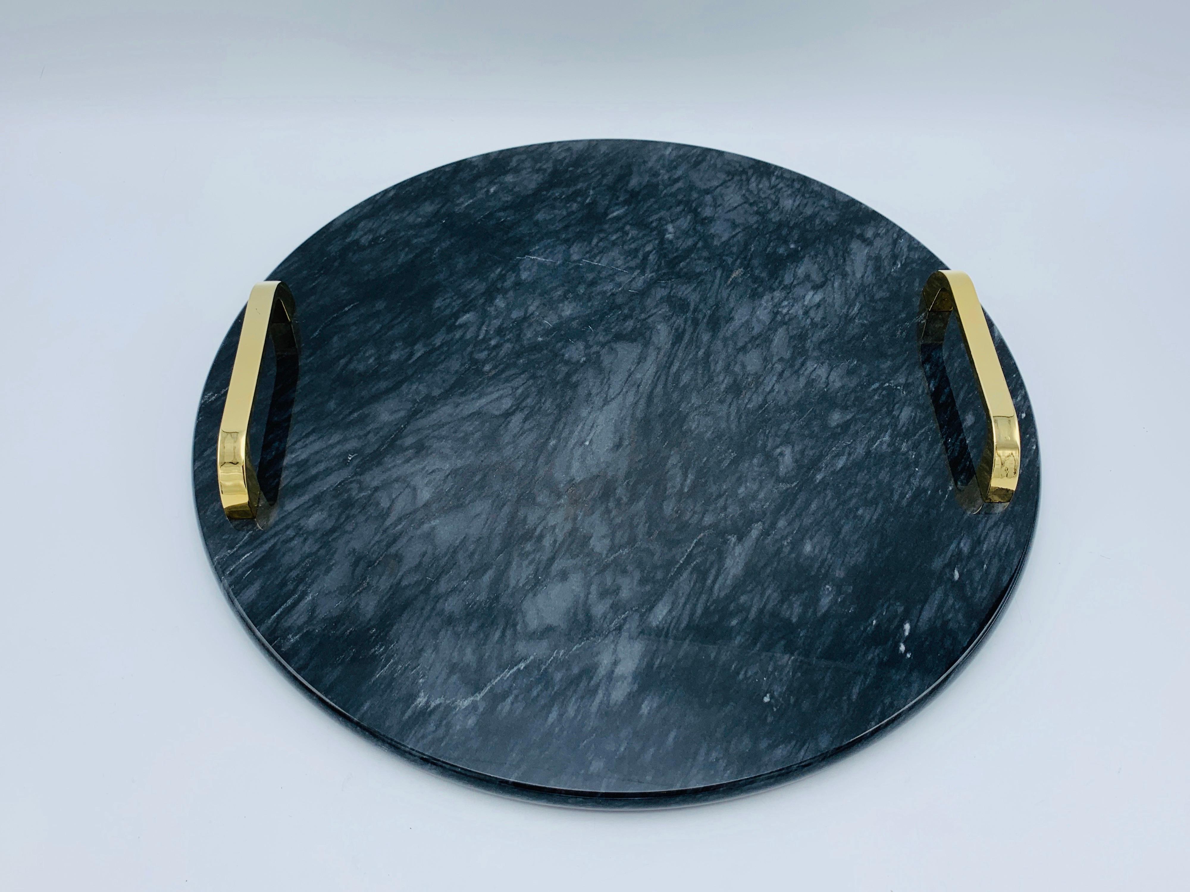 Listed is a modern and sophisticated, 1970s Italian black and white/gray marble tray with heavily polished and lacquered brass handles. Gorgeous natural veining throughout the polished stone. Marble is .5in thick. The overall piece is heavy,