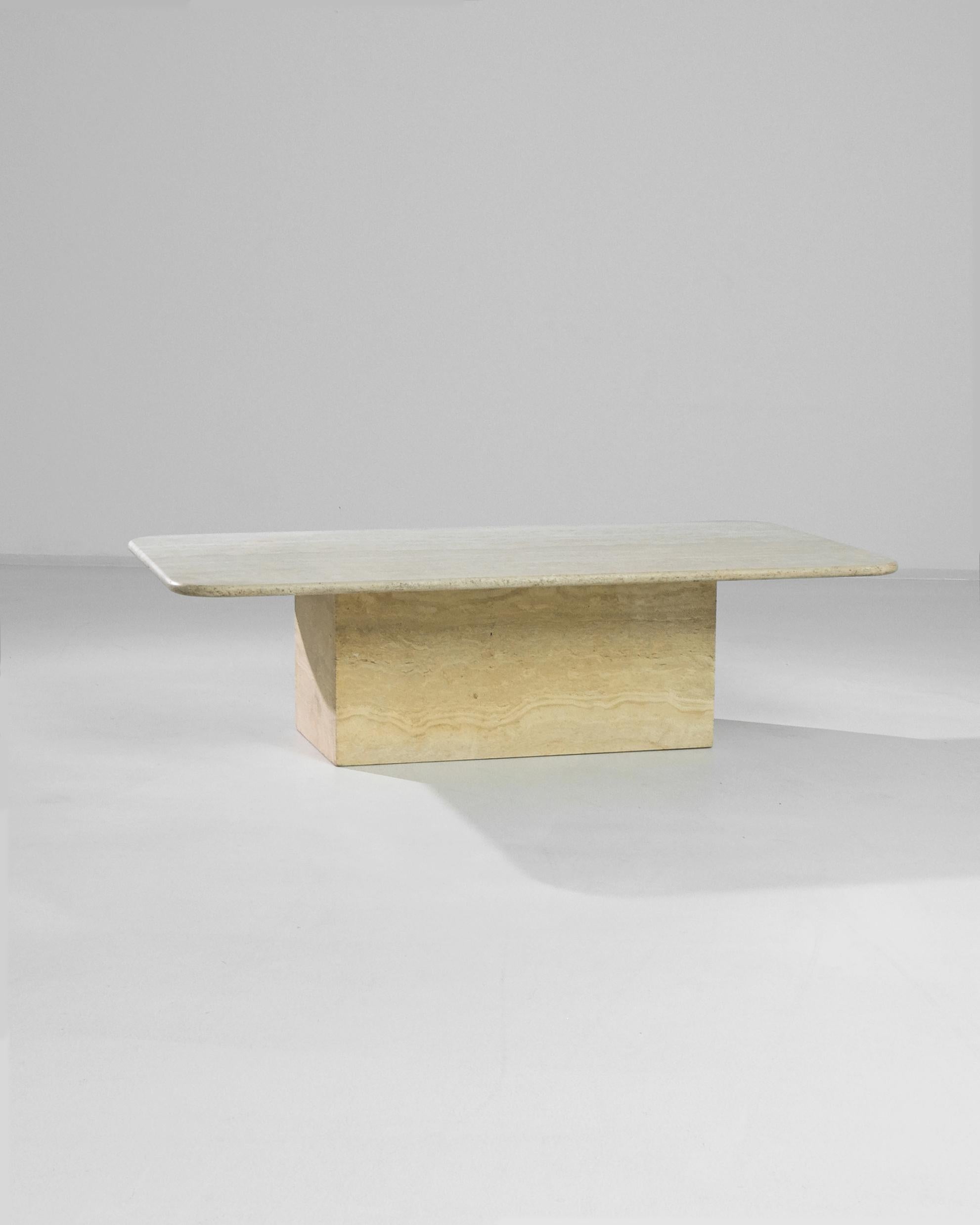 The formal simplicity and beautiful color of this travertine marble coffee table create an impression of minimalist luxury. Made in Italy in the 1970s, an oblong tabletop with gently rounded corners sits atop a low rectangle of stone. The butter