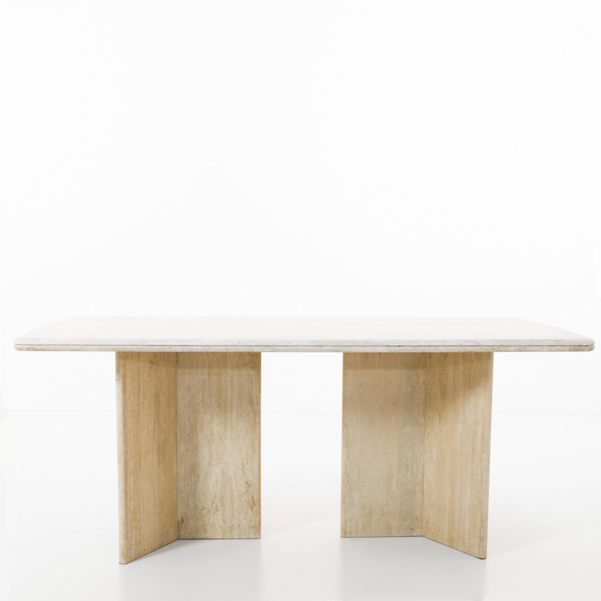 A marble dining table produced in Italy circa 1970. Standing on two three-point bases, this solid travertine table shall not be moved. The 70 inch tabletop can comfortably fit 6-8 on its sleek two-tone finish that’s been polished till it shines. An