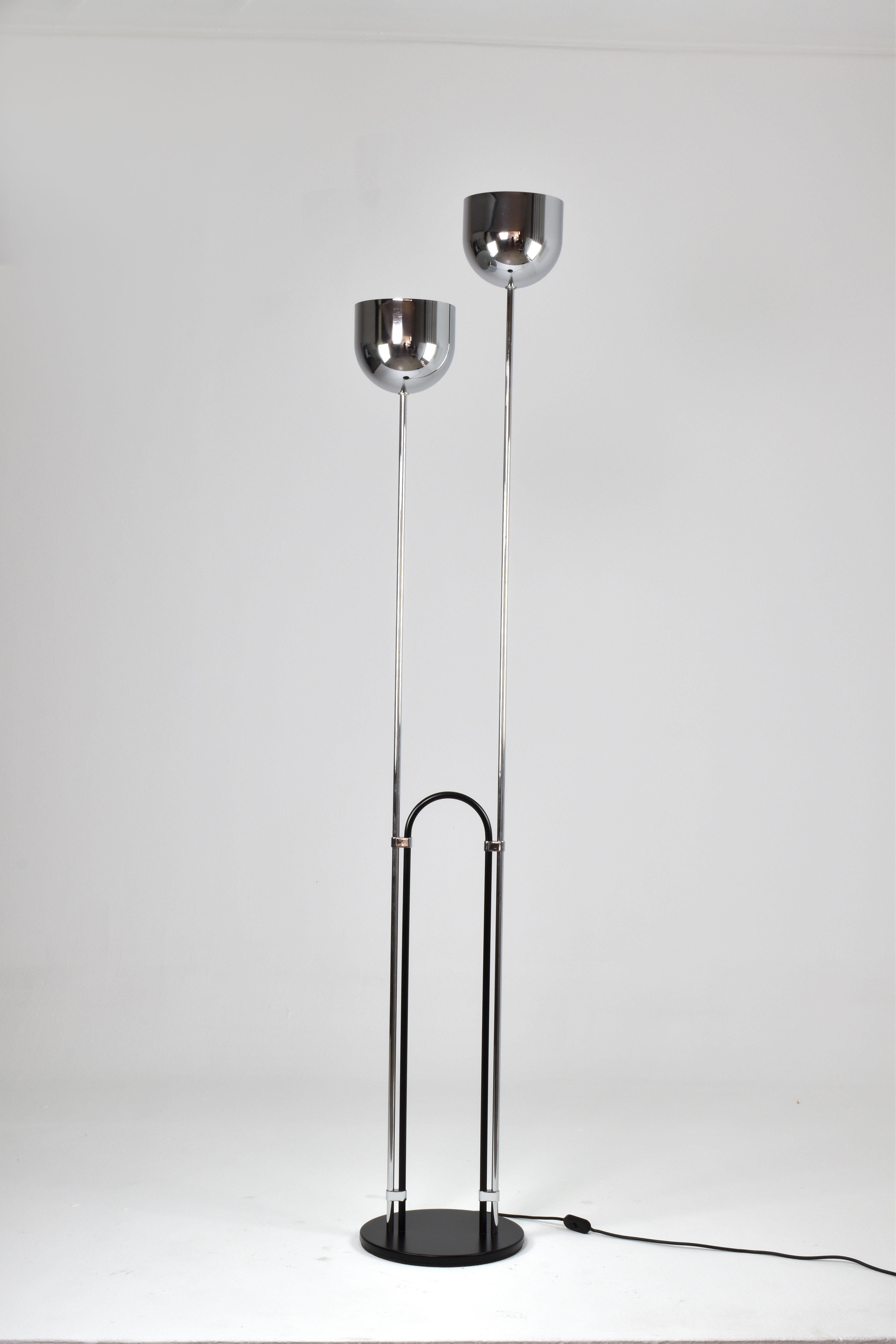 A stylish floor lamp from 1970s Italy, attributed to Reggiani. This distinctive piece features two chrome stems with upward-facing shades, casting a gentle, ambient glow towards the ceiling. Connecting these stems is a sleek circular tube, adding to