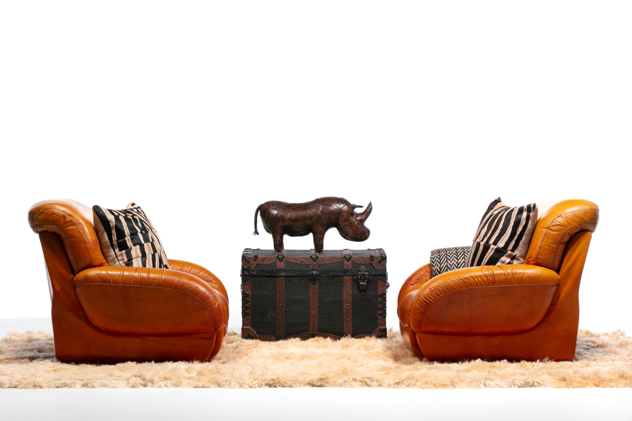 This pair of mid century modern Italian leather club chairs hits all the marks with a high design modern silhouette, warm and inviting original carmel color leather upholstery that pairs with all color schemes, and an all encompassing comfortable