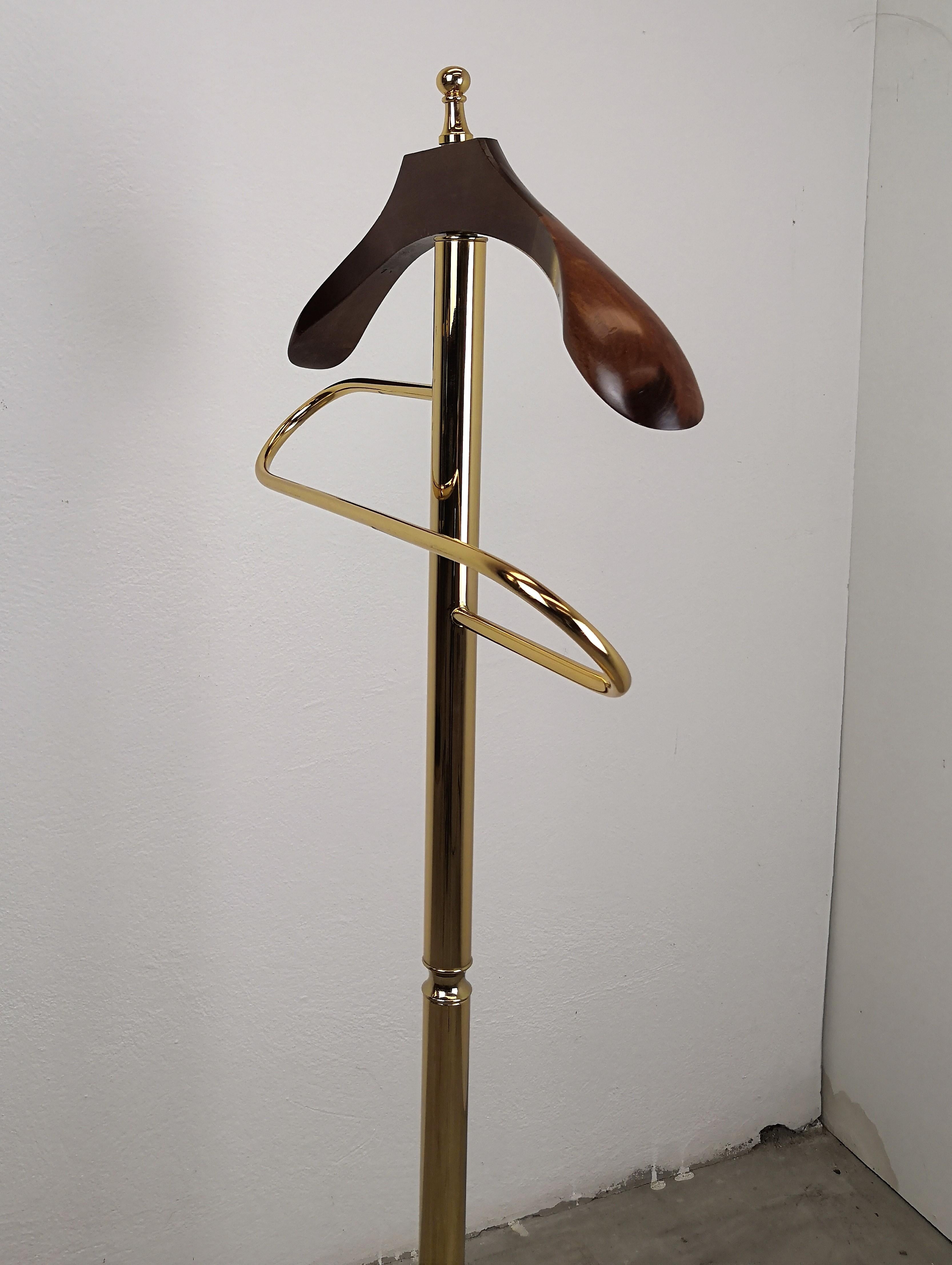 Beautiful 1970s Italian brass and wood dressboy valet stand, designed and manufactured in Italy. The valet has a wooden clothes hanger, a gorgeously shaped reling to hang pants and a marble pedestal, stand.

A great piece that perfectly adds to