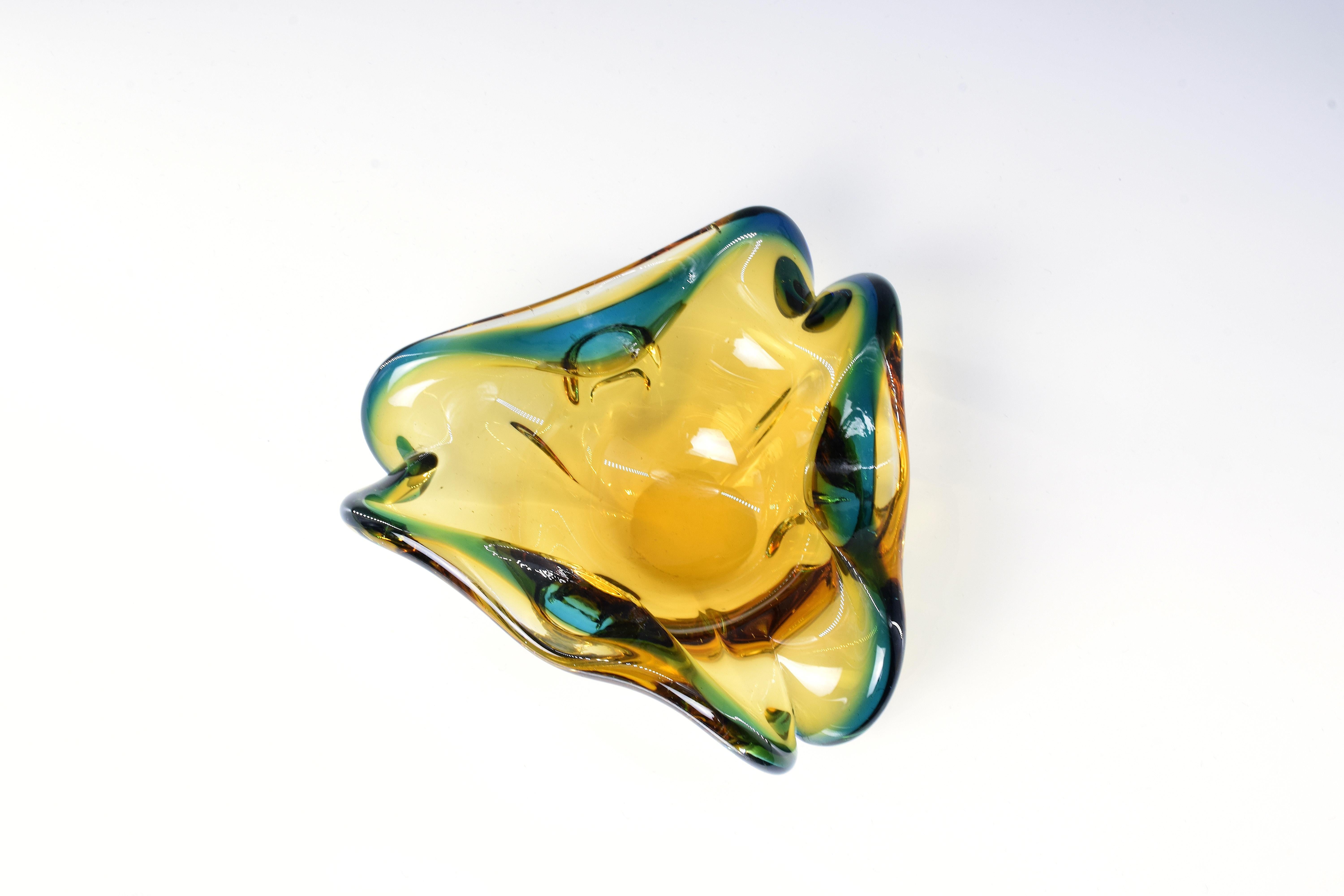 An exquisite small Murano glass decorative bowl in unique shape that could also be used as a stylish ashtray, a perfect add up to your interior decorative collection. This 1970s Murano glass piece is made following the Sommerso technique, which