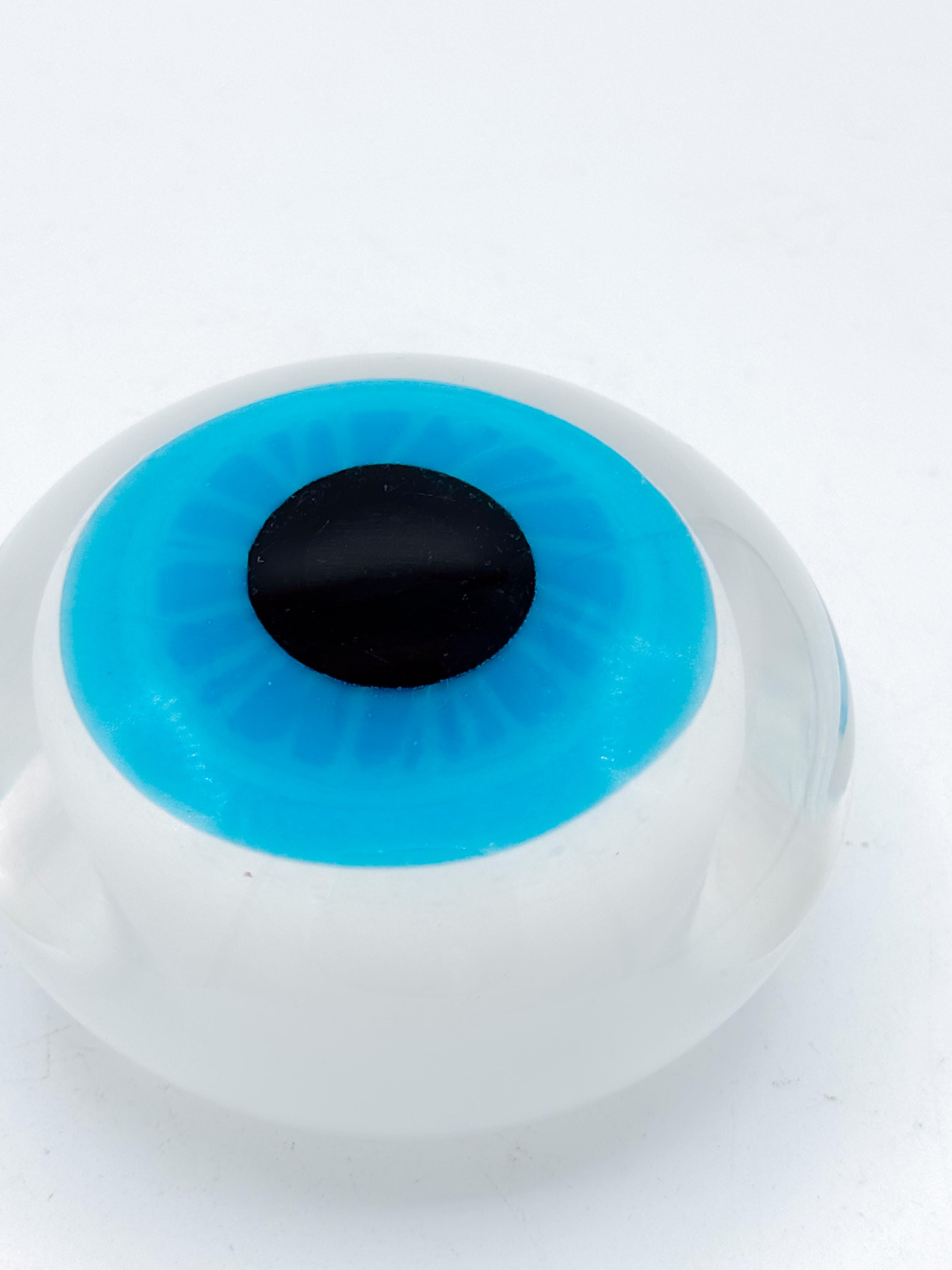 A striking 1970s Italian Murano-style hand-blown glass eye paperweight, crafted with a vivid turquoise iris encased beneath a clear, domed glass surface. This sculptural piece captures the playful surrealism and optical experimentation