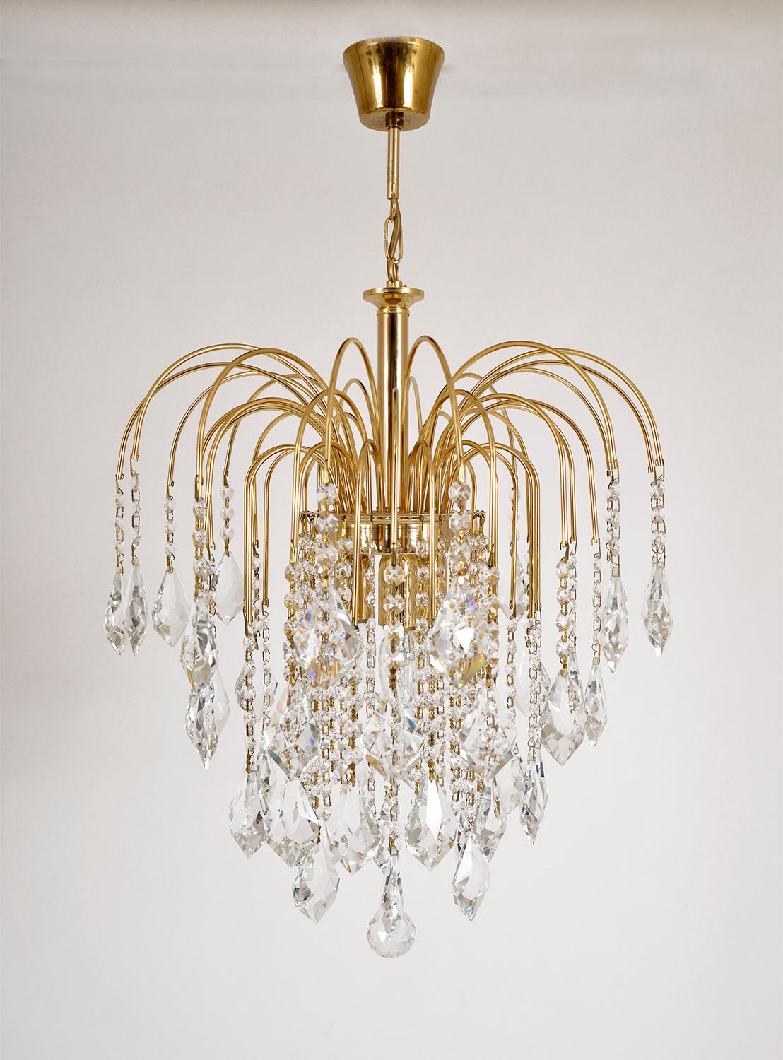 This vintage Italian waterfall chandelier features a gilt brass frame with multiple tiers, which teems with strands of sparkling cut crystal, topped off with elegant diamond faceted teardrop crystals and a crystal ball. 
Three bulbs illuminate the