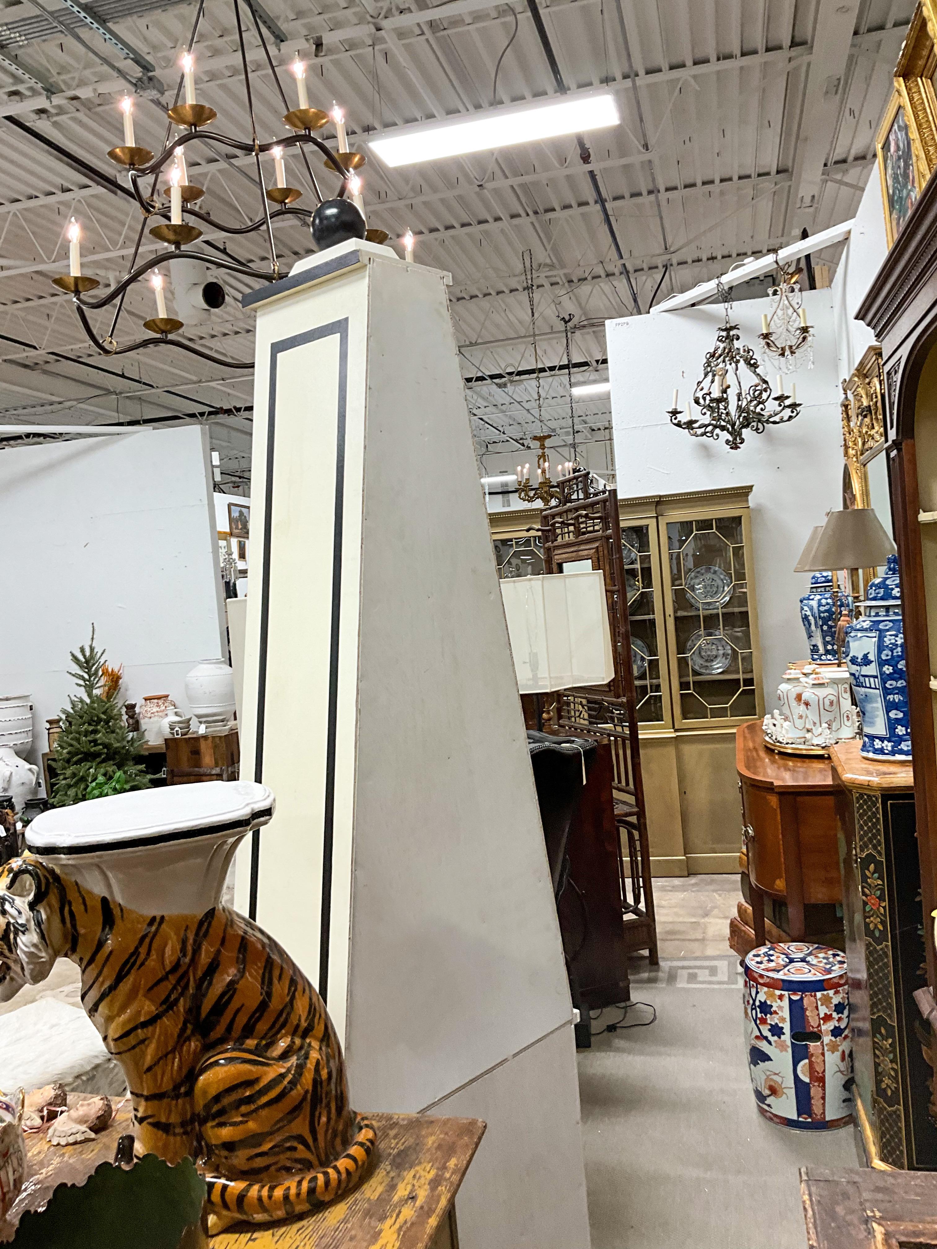 I love these! The cream body with black trim give these obelisk form bookcases / etageres a dramatic appearance. Your collections would pop with the neutral background. They are unmarked and in very good condition. The shelves are not adjustable.