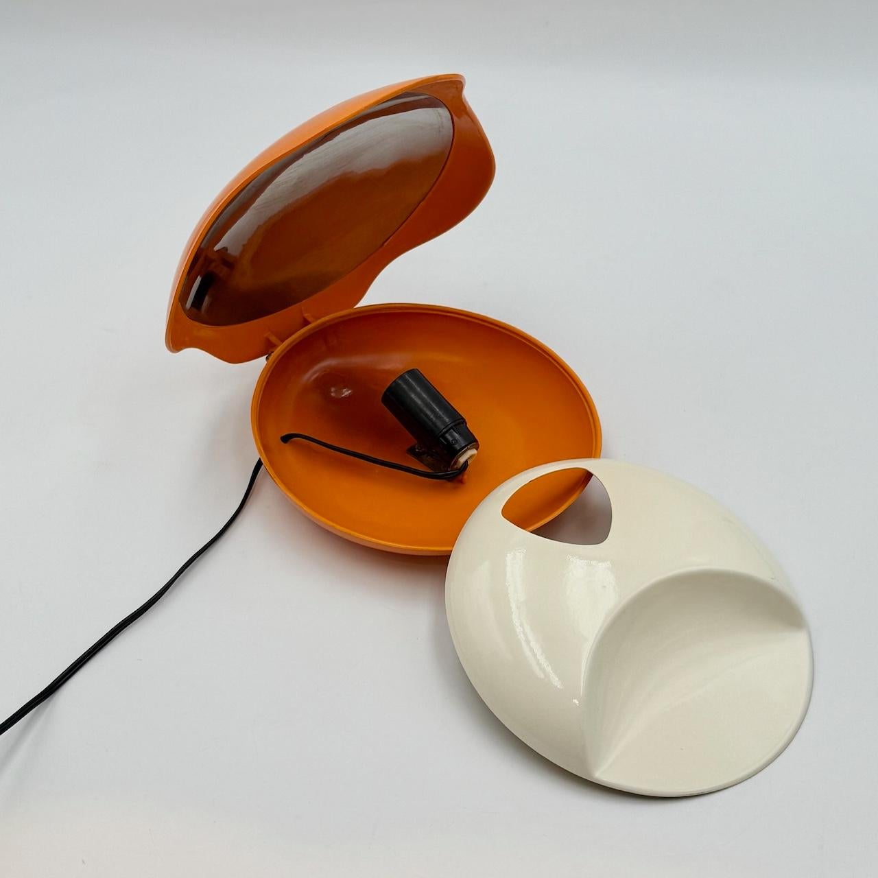 La lampada Orange Oyster di Gamma3 è un autentico pezzo di design italiano dell'era spaziale degli anni Settanta. Si distingue per la sua forma ovale, simile a un'ostrica, e per il suo colore arancione vivo, esemplificando il fascino dell'epoca per
