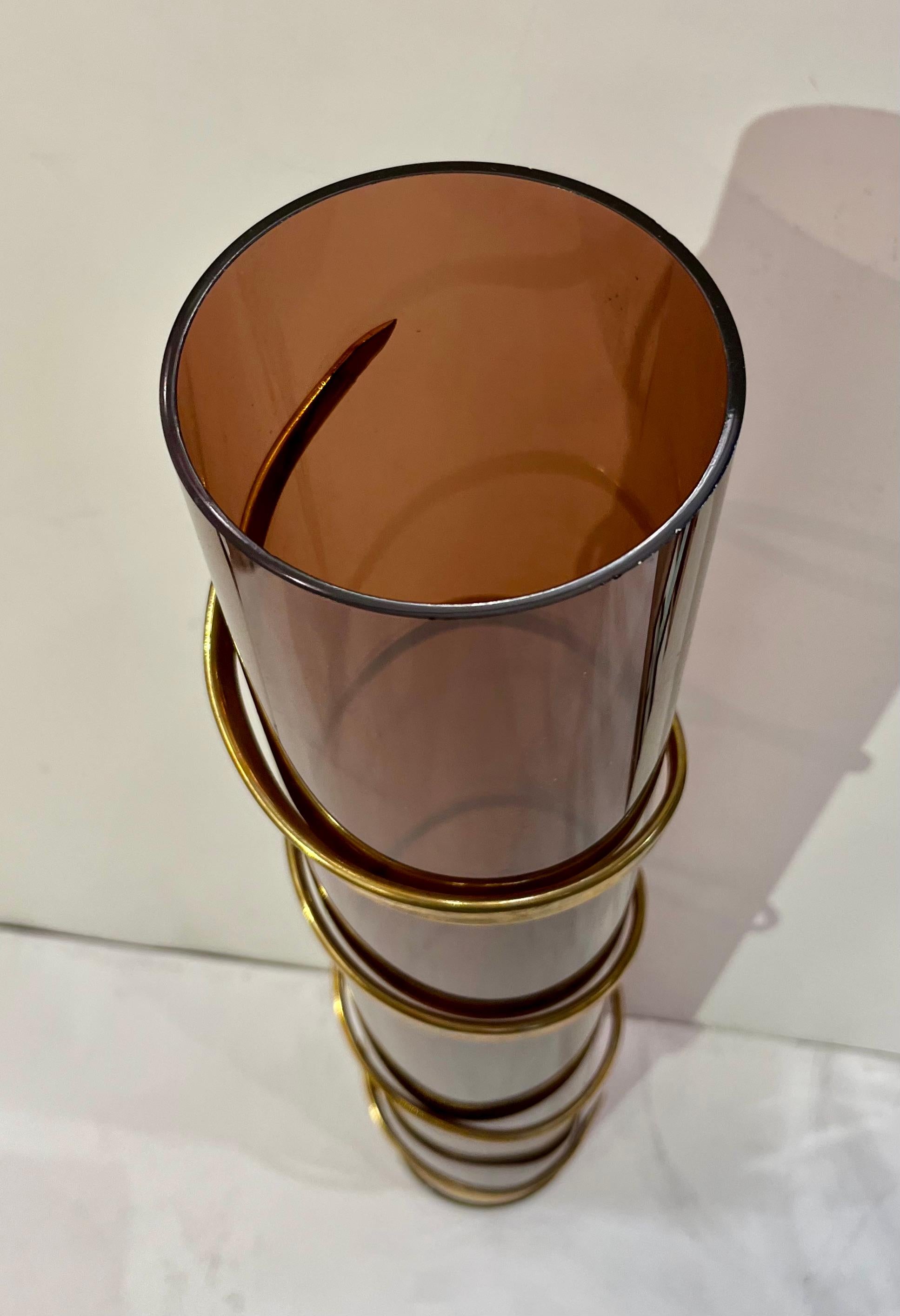 Vintage Mid-Century Modern Italian Design cylindrical sculpture vase, attributed to Romeo Rega, tall and slender, the organic body in transparent brown acrylic is decorated with a brass Egyptian style sinuous spiral on the outside, finishing with a