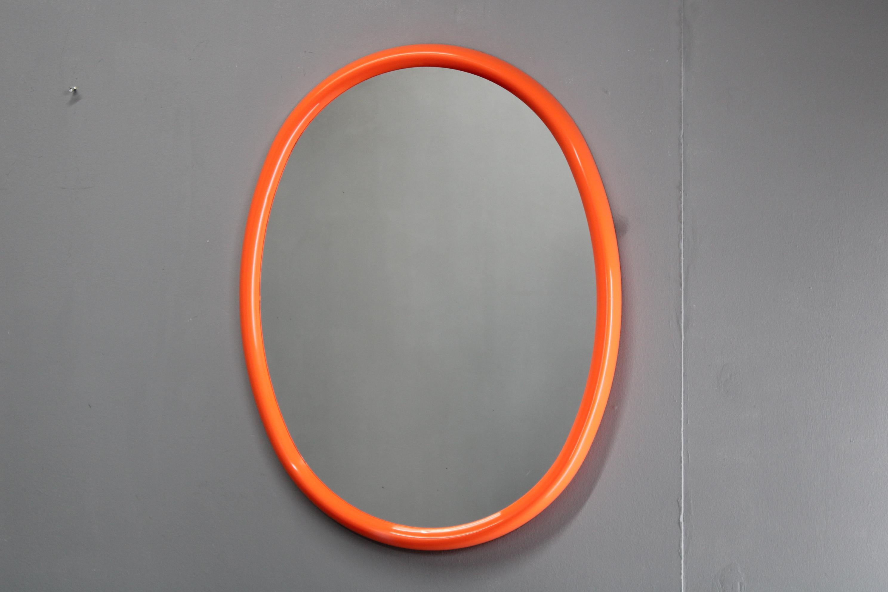  Llamativo espejo ovalado vintage de los años 70 procedente de Italia, con marco moldeado de plástico de color naranja vibrante y cristal de espejo de calidad. Su perfil retro y su color atrevido lo convierten en un acento ideal para interiores
