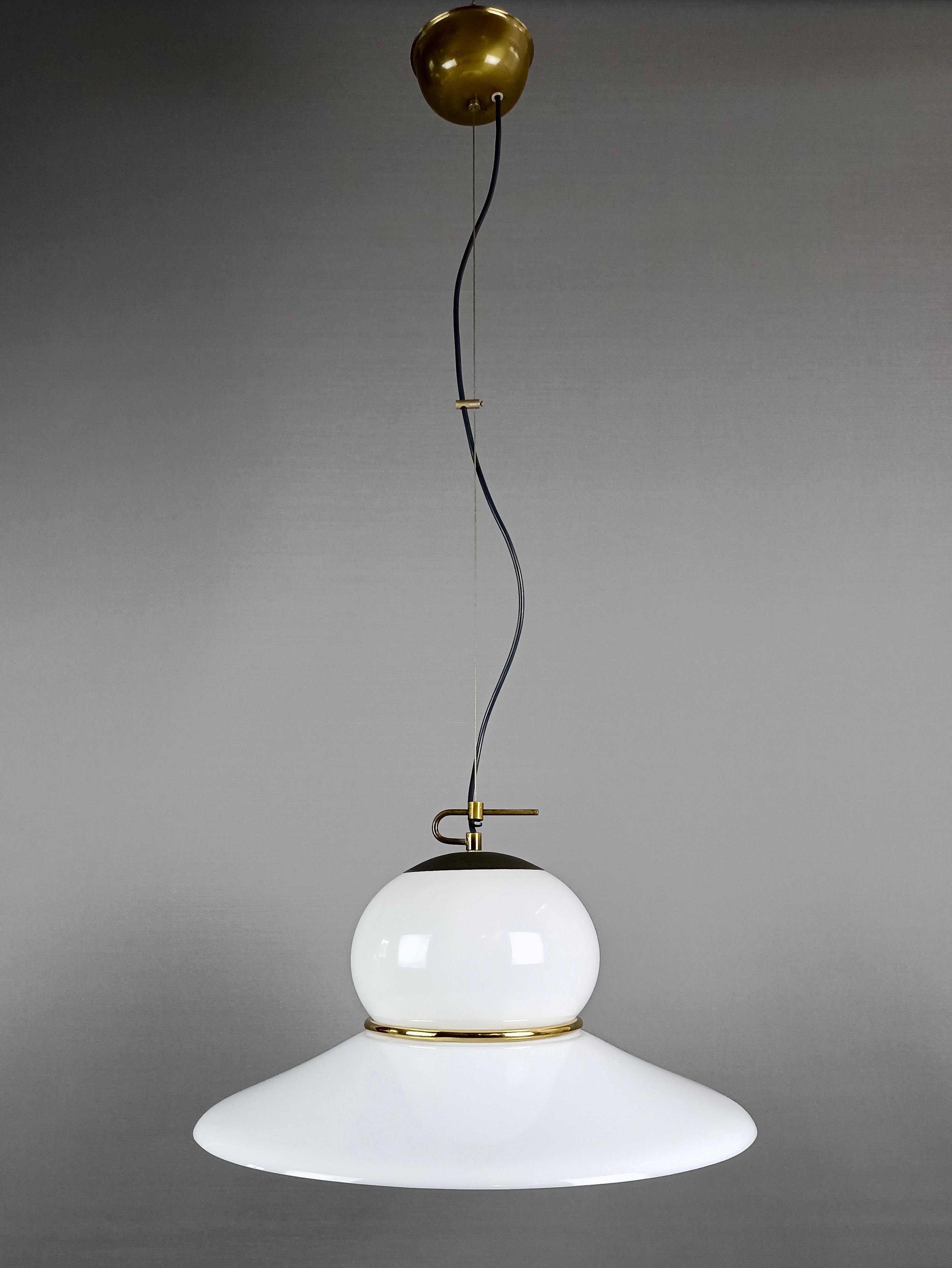 Italian 1970s pendant lamp with white plastic lampshade, burnished brass structure and steel cable fixing to the ceiling.
With its unusual shape it is a beautiful piece of furniture both when turned off and when on. 
The lampshade is made of