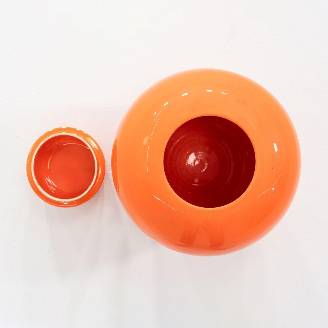 Si tratta di un grande vaso in porcellana arancione, realizzato a mano in Italia negli anni '70 circa. Conserva il suo piano originale a coppa coordinato. C'è un adesivo Made in Italy che rimane attaccato alla parte inferiore del pezzo, a indicare