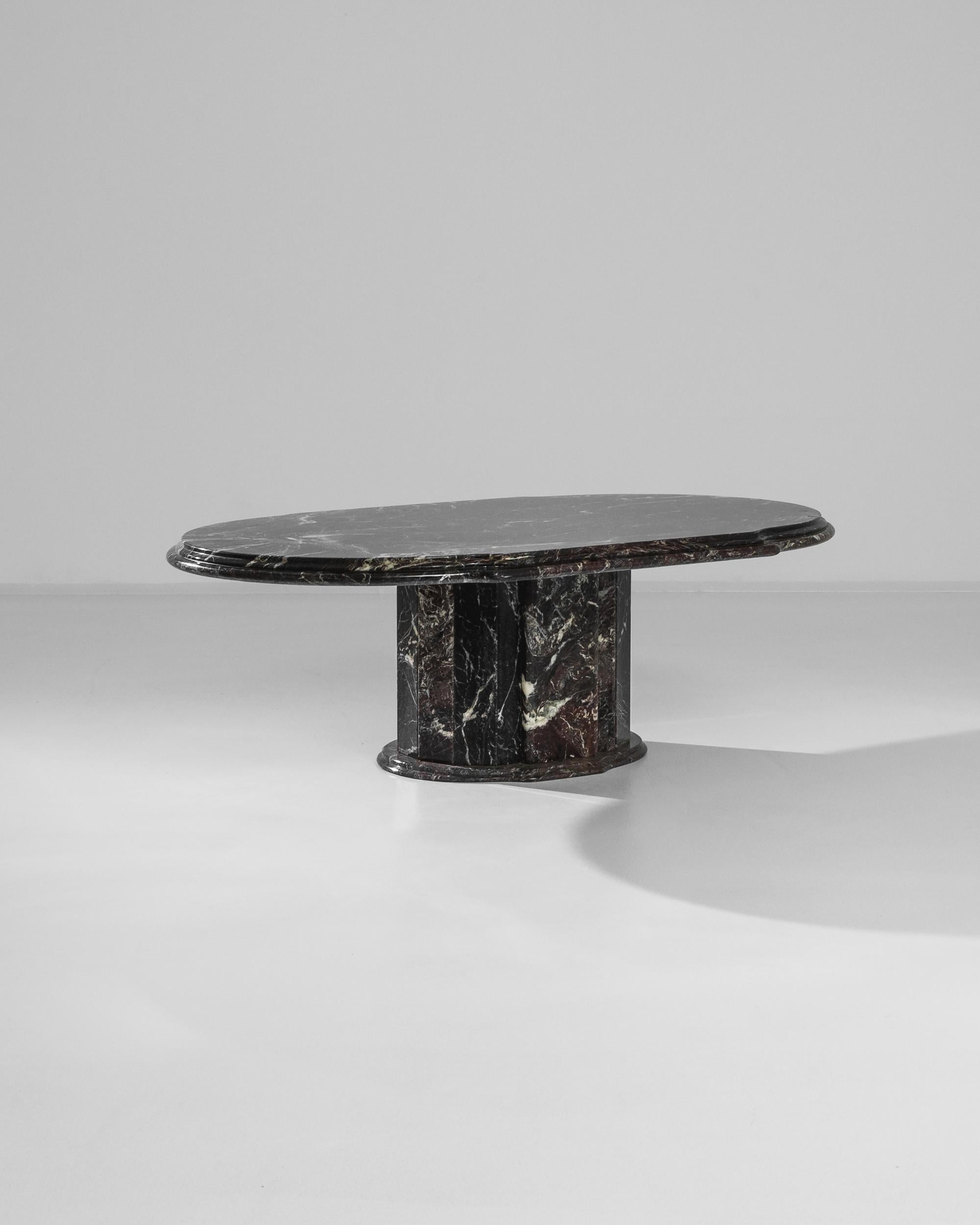 An Italian 1970s large black marble coffee table. Minimal and confident in its construction, yet detailed in its natural patterning, this coffee table exudes a palpable regality. Stria of white and gray run through the stone, offering an exciting