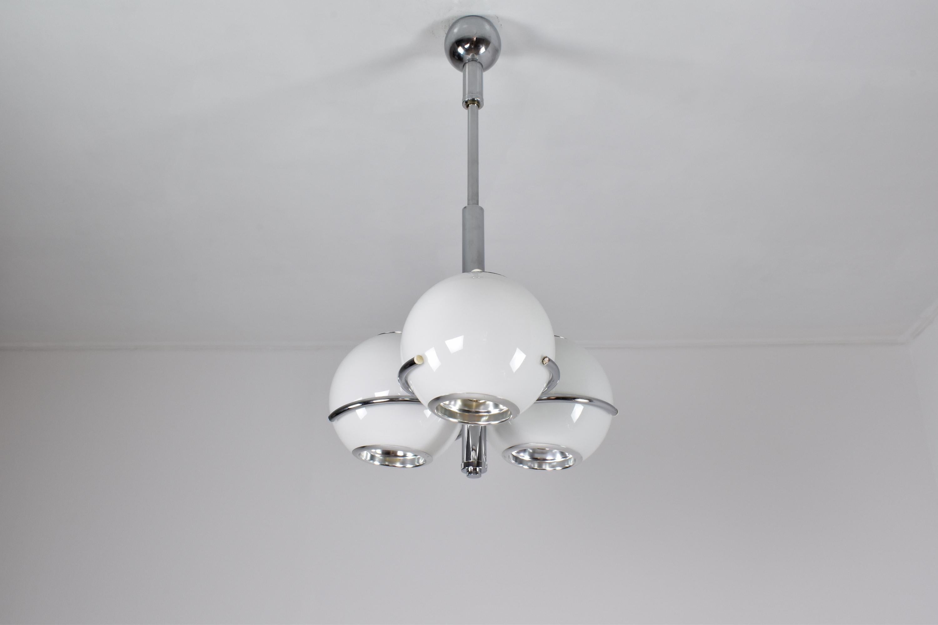 A 20th-century vintage pendant by notable Italian manufacturer Reggiani from the 1970's. This lighting piece is in beautiful condition and is designed with a chic stainless steel structure and three opaque glass globe-shaped shades. 
This piece is