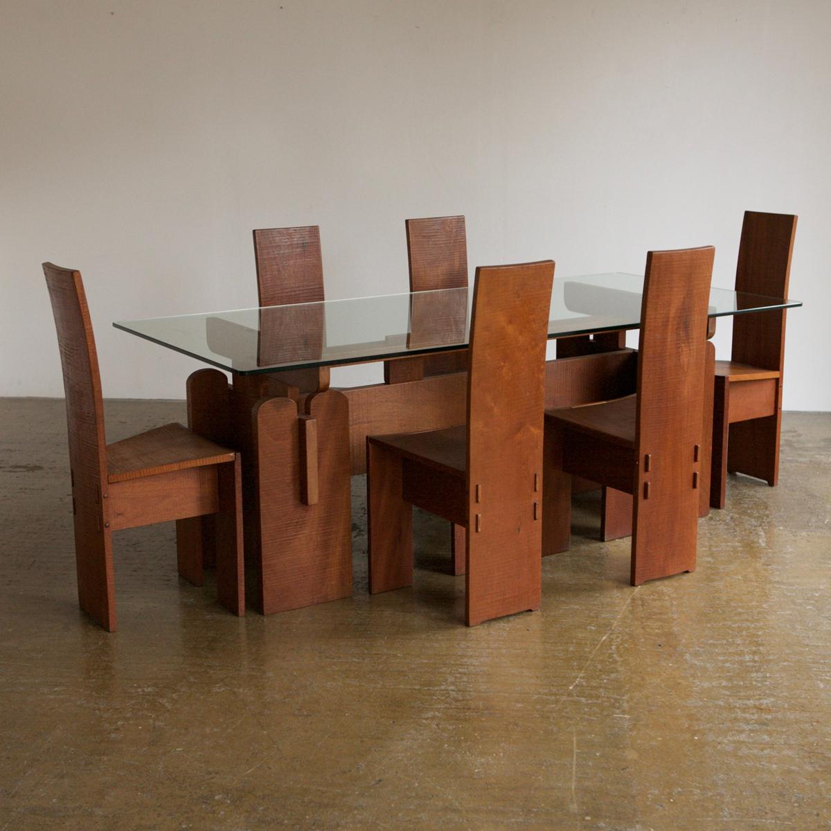 This table and 6 chairs from 1970's Italy is attributed to Guiseppe Rivadossi, but the piece is unsigned. The solid walnut table base and chairs have a carved textured surface and the design is characteristic of the Rivadossi style in which the