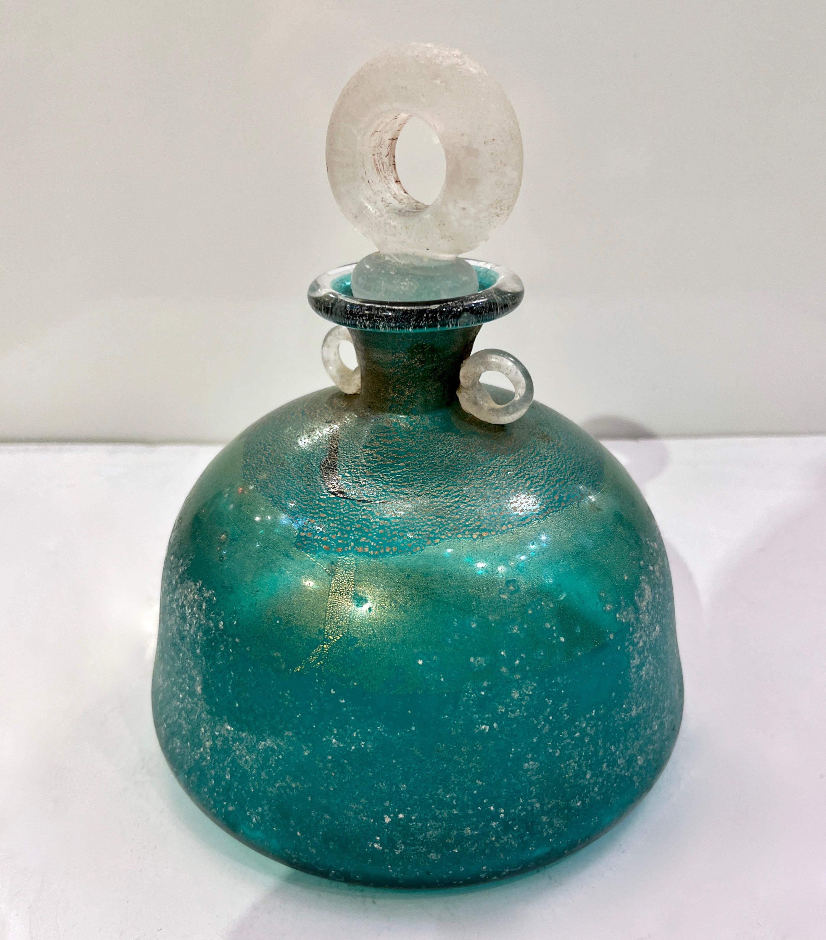 Une fabuleuse paire de bouteilles en verre de Murano turquoise signées Gambaro & Poggi, avec des poignées et des bouchons en scavo blanc, travaillées avec des feuilles d'or 24 Kt dans le verre. Haute qualité d'exécution.
Le corps en verre de couleur