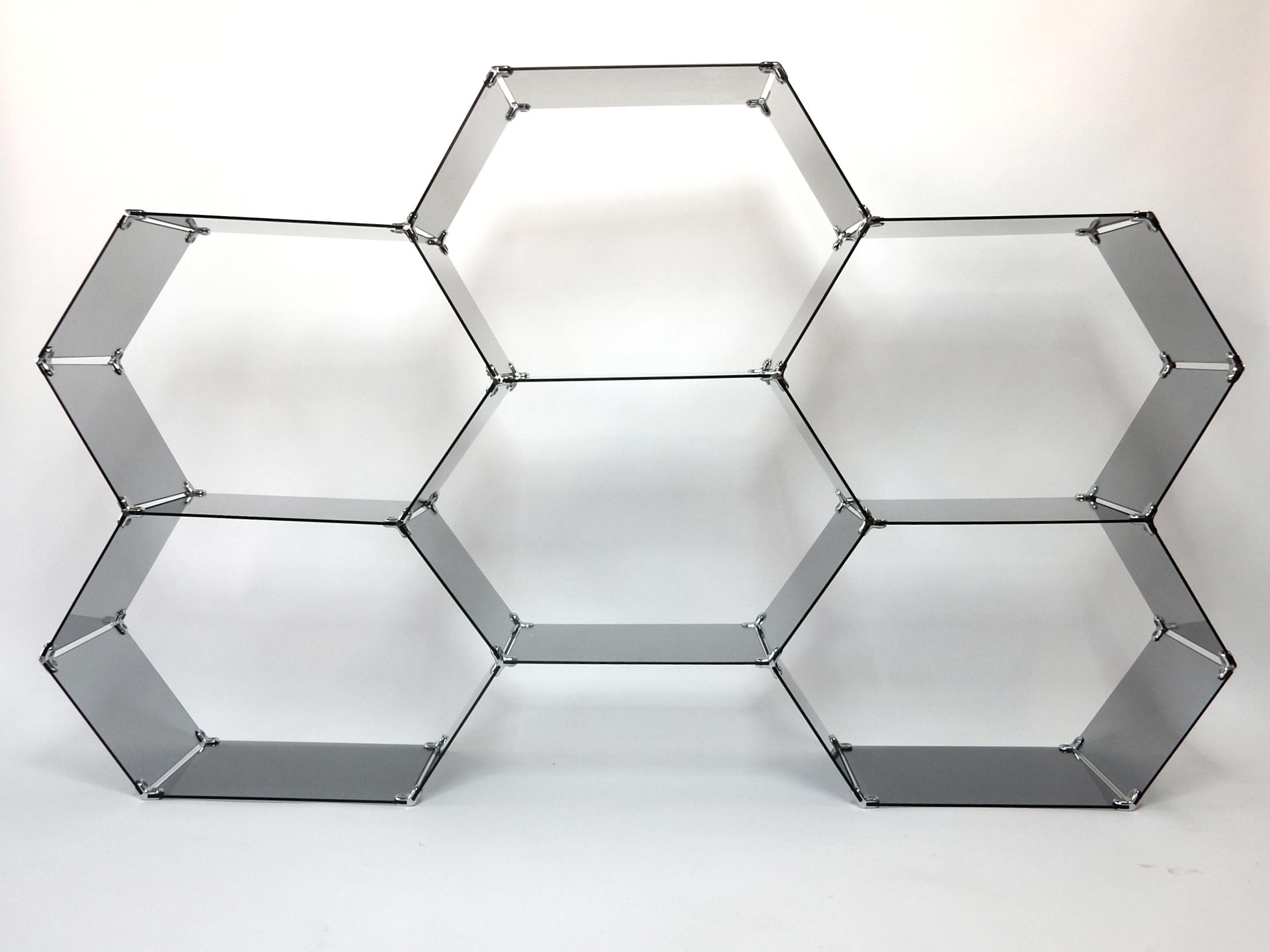 Hexagonal honeycomb display étagère.
Interconnected smoke glass plates fastened via chromed metal clips creating 6 hexagonal spaces to display your most cherished collection.
Measures: 6 feet wide x 45 inch tall. This can be assembled to go on top