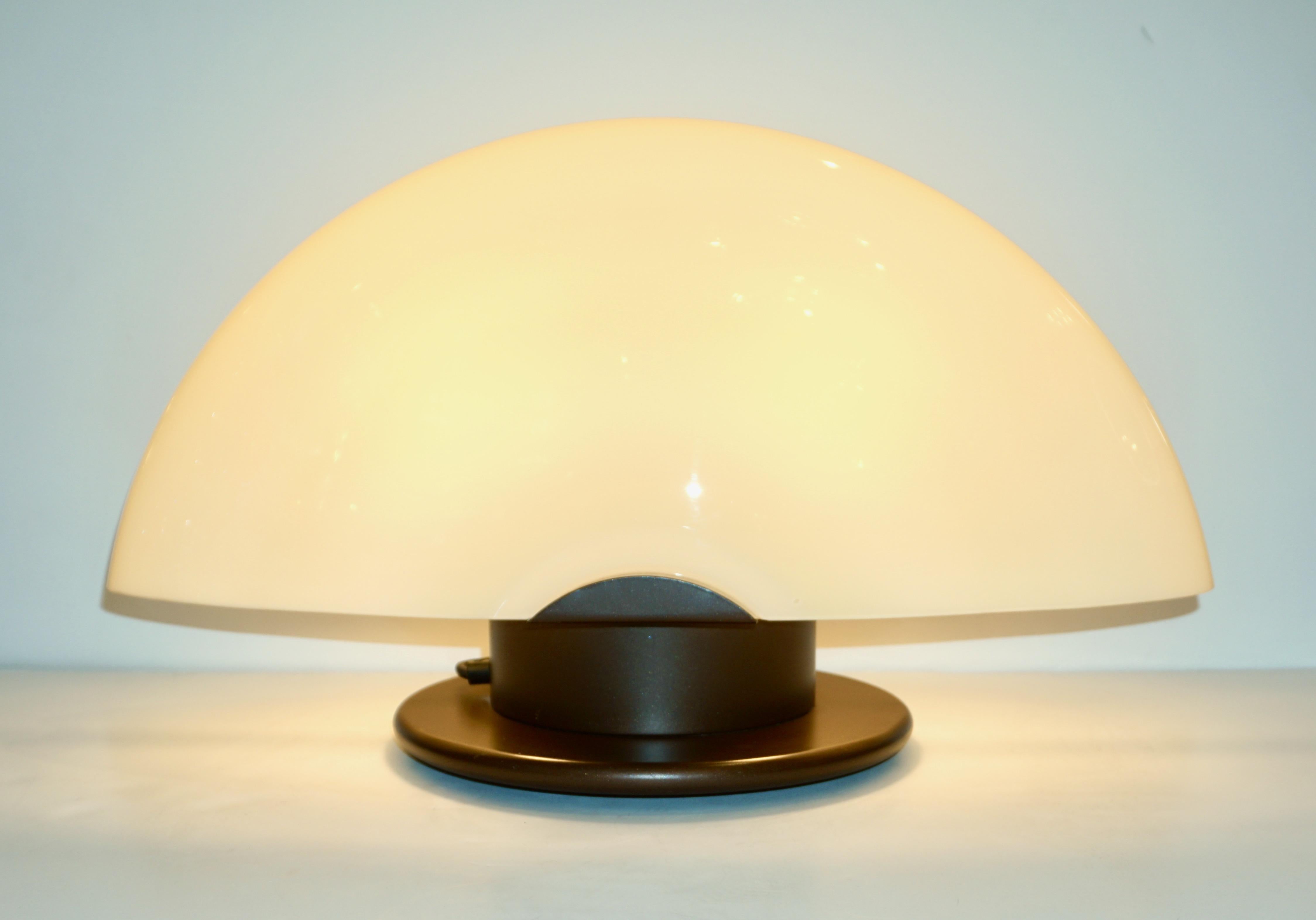A vintage pair of modern design desk / table lamps by Mazzega with an atomic age flair, entirely made in Italy, consisting of a round metal base lacquered in a copper brown finish supporting a demilune shade in a warm ivory cream Murano glass