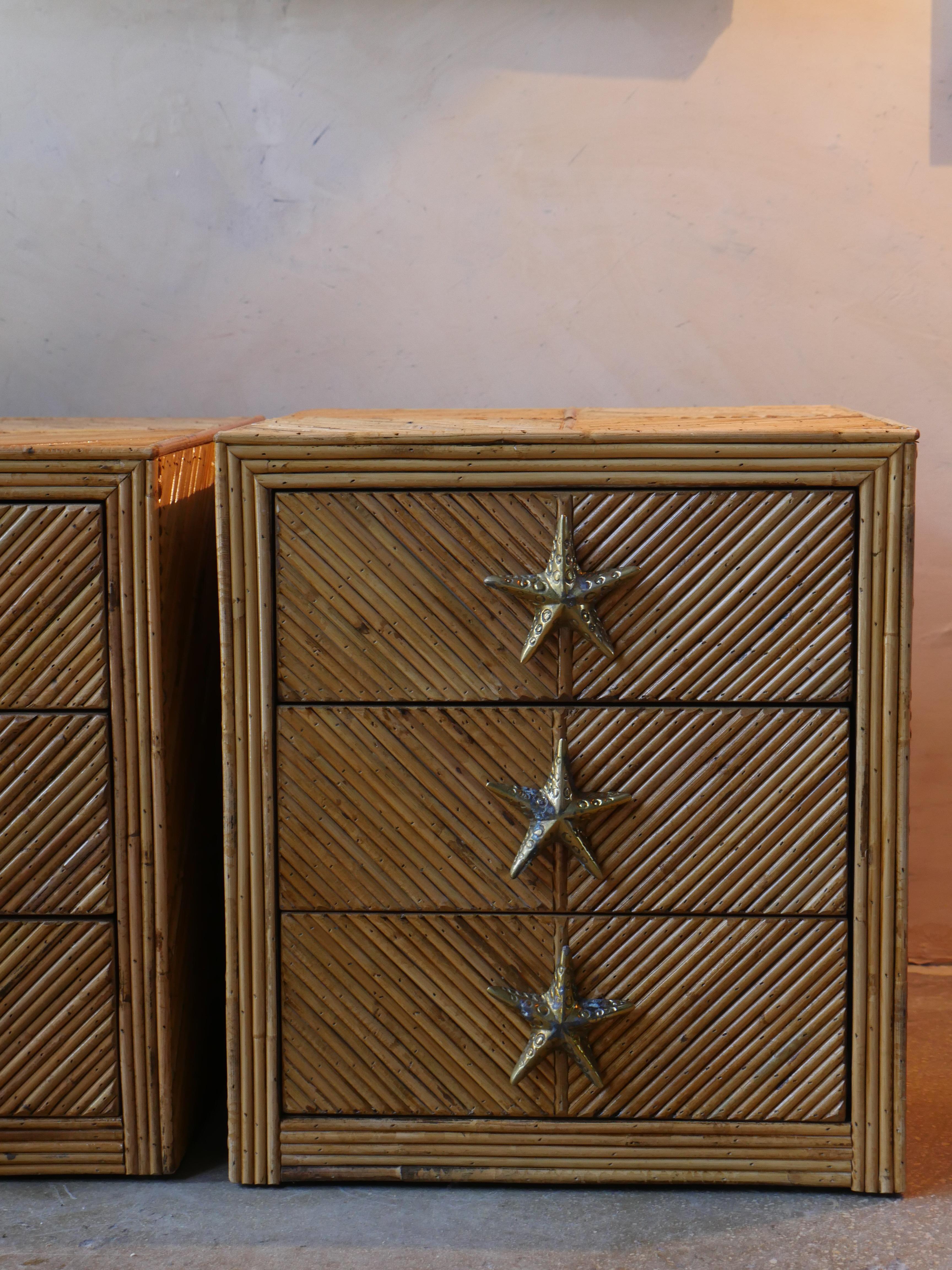 A charming pair of 1970s Italian designer nightstands wrapped in split pencil reed bamboo with beautifully patinated brass starfish pulls. Each nightstand features three drawers that glide smoothly. The natural texture of the bamboo brings warmth