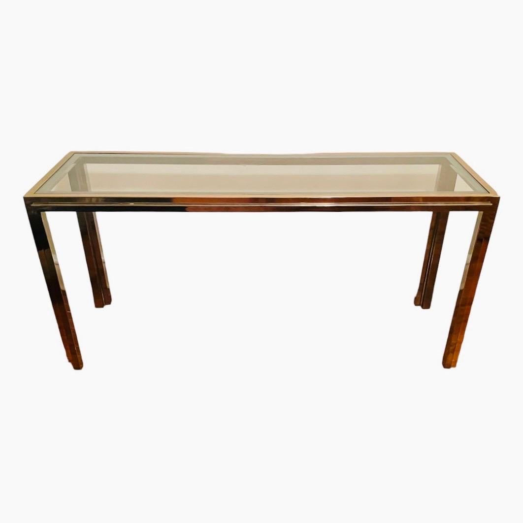 This is a stainless steel and brass console table, with a thick inset glass top. It dates to the 1970s and is very much in the style of Willy Rizzo's 