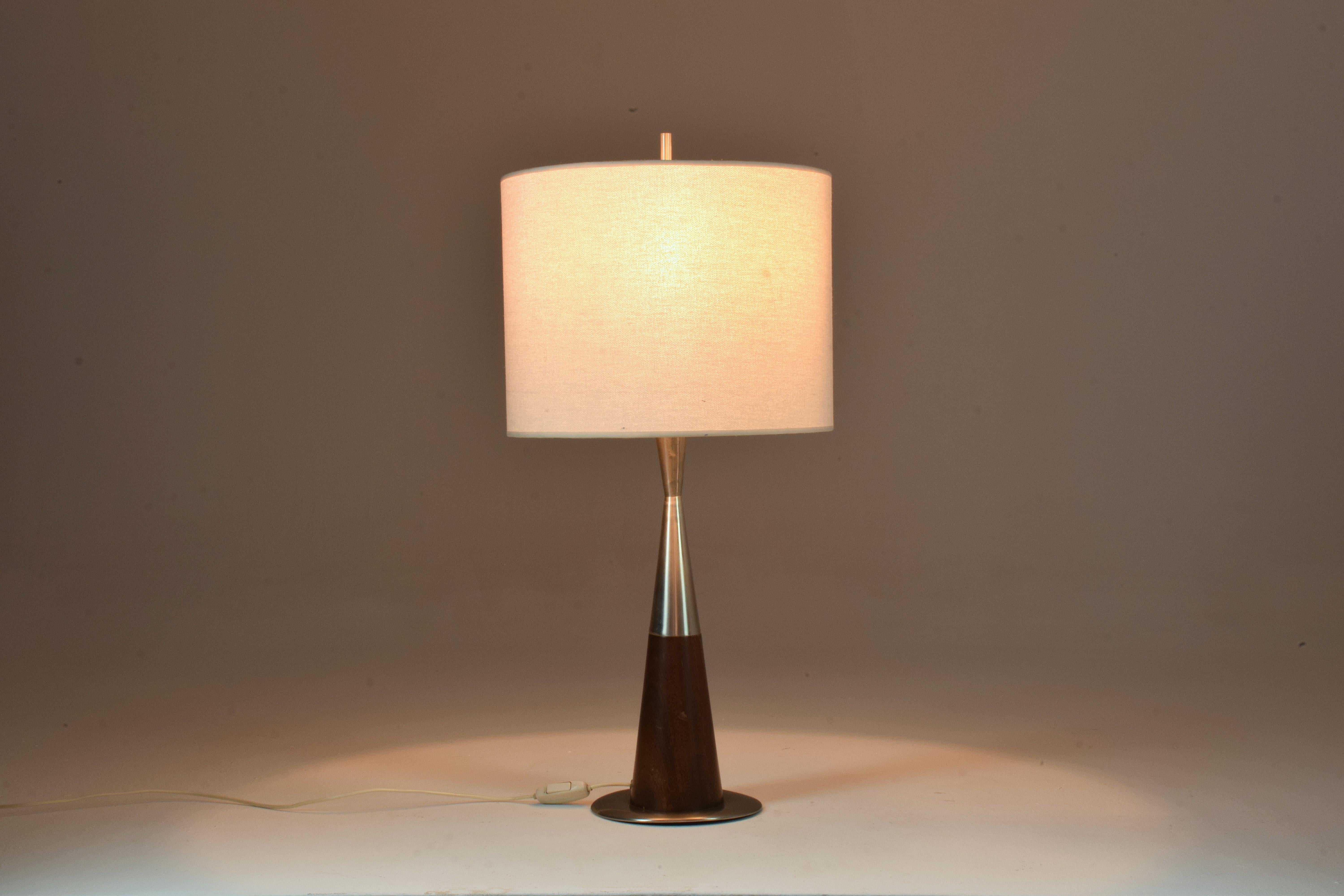 A 20th-century tall vintage table lamp designed in a chic triangular stainless steel mix solid mahogany structure. 
In fully restored condition with a new fabric cylinder shade. Labeled. 
Italy. 1970's



We are an exhibition space and an online
