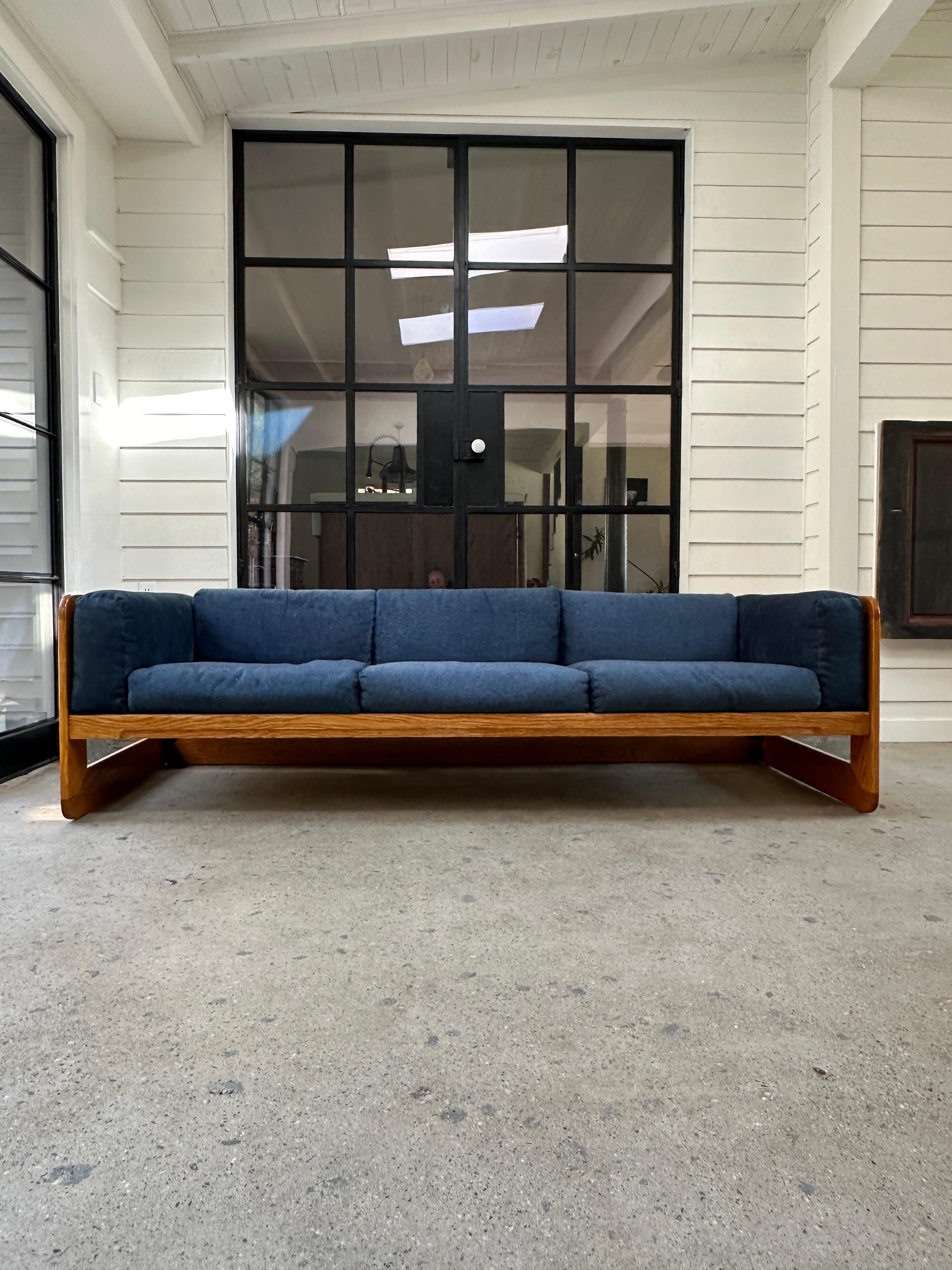 1970s oak framed three seater sofa designed by Giuseppe Raimondi. Minor flaws on the frame indicative of the age of the piece. Dark blue upholstery in good condition, showing no signs of stains.

Springs are not original.

Matching set of lounge