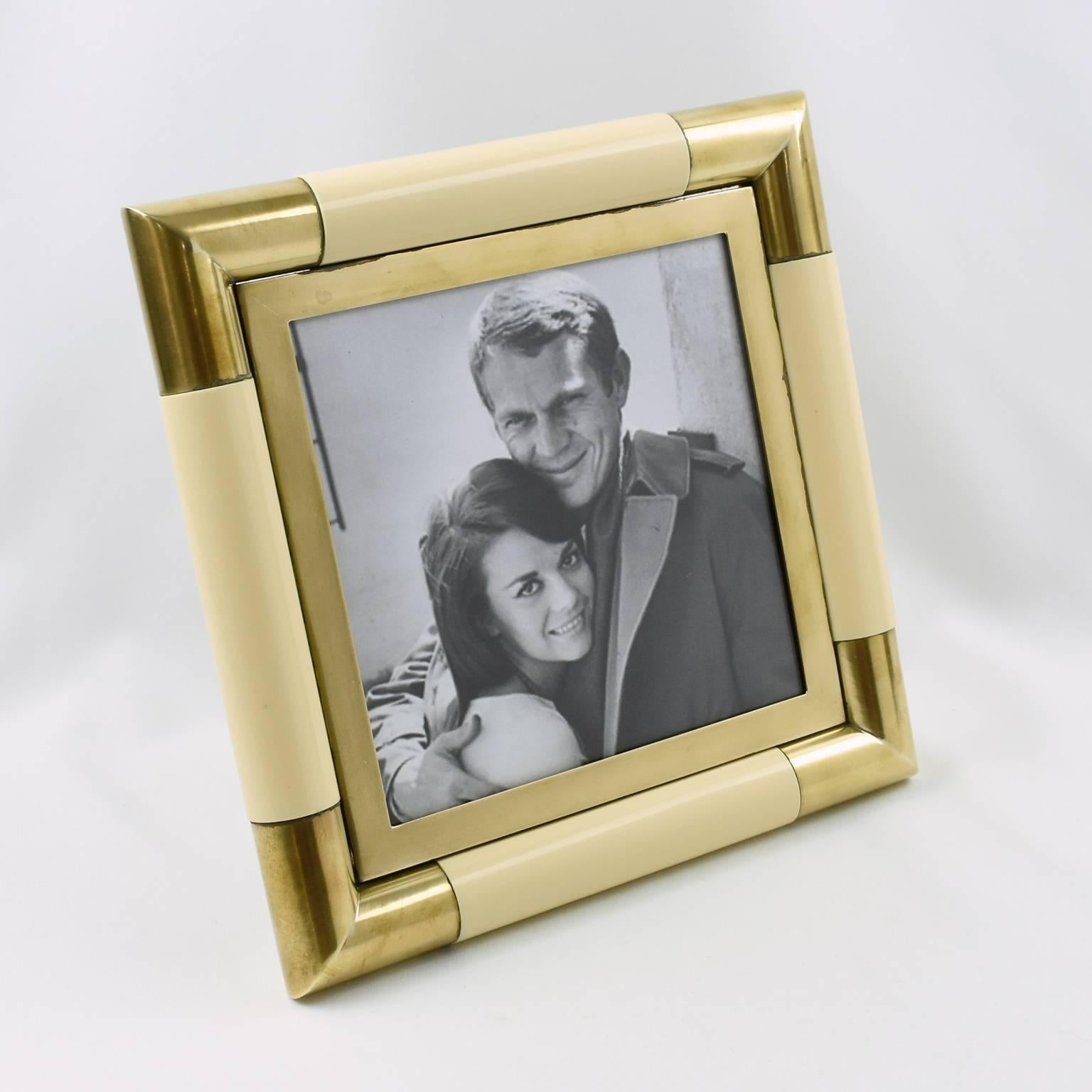 Stunning picture photo frame designed by Tommaso Barbi, Italy. Mid-Century modernist square shape with curvilinear edged brass framing compliment with ivory color lacquer. Easel and back in brown watered fabric.
Measurements:
Overall: 10.25 in. wide