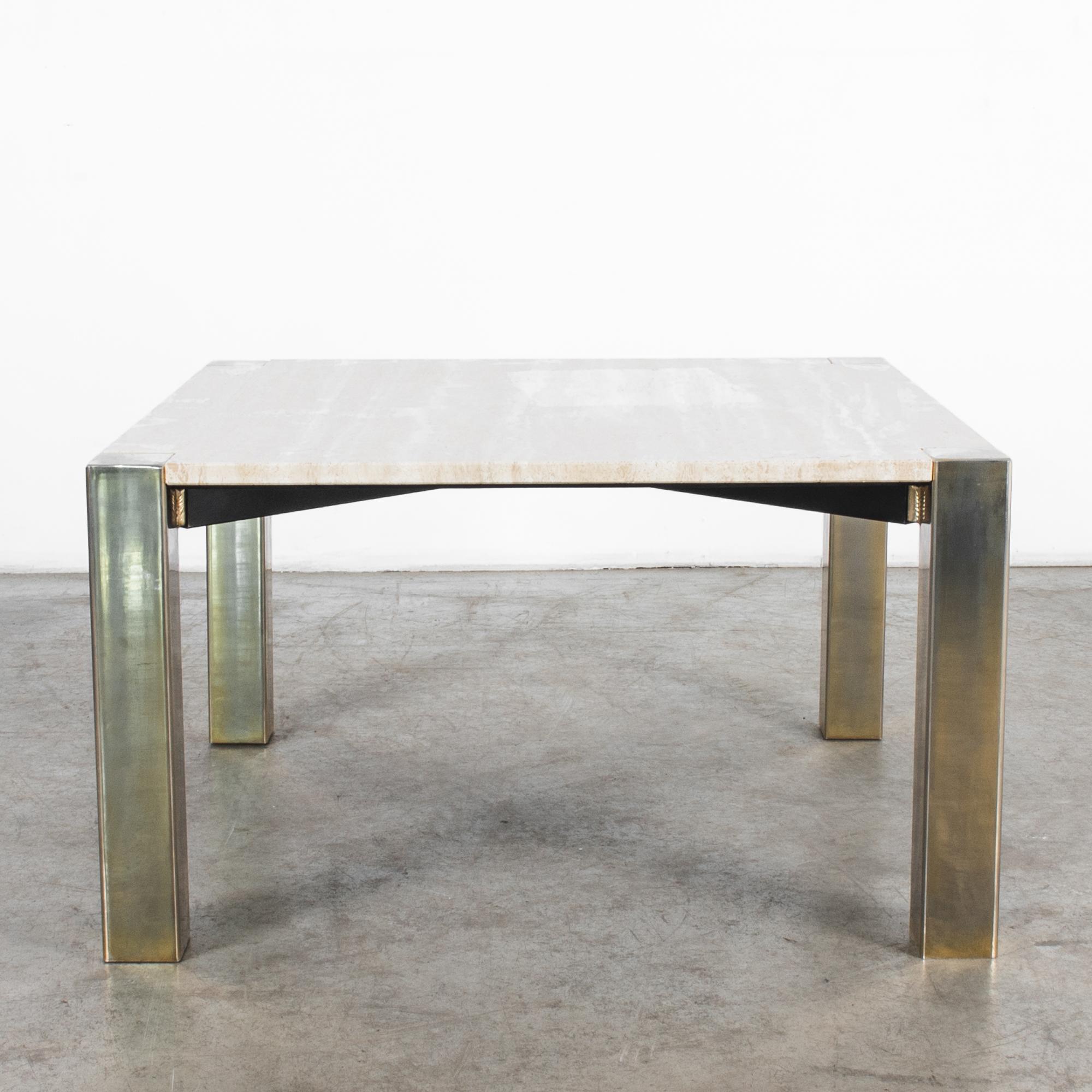 A sleek design from Italy, minimal metal legs, plated in brass, hold a square travertine top in this 1970s coffee table. 80 centimeters by 80 centimeters, carefully polished and cut, the brass legs interlock with stone to complete the stark