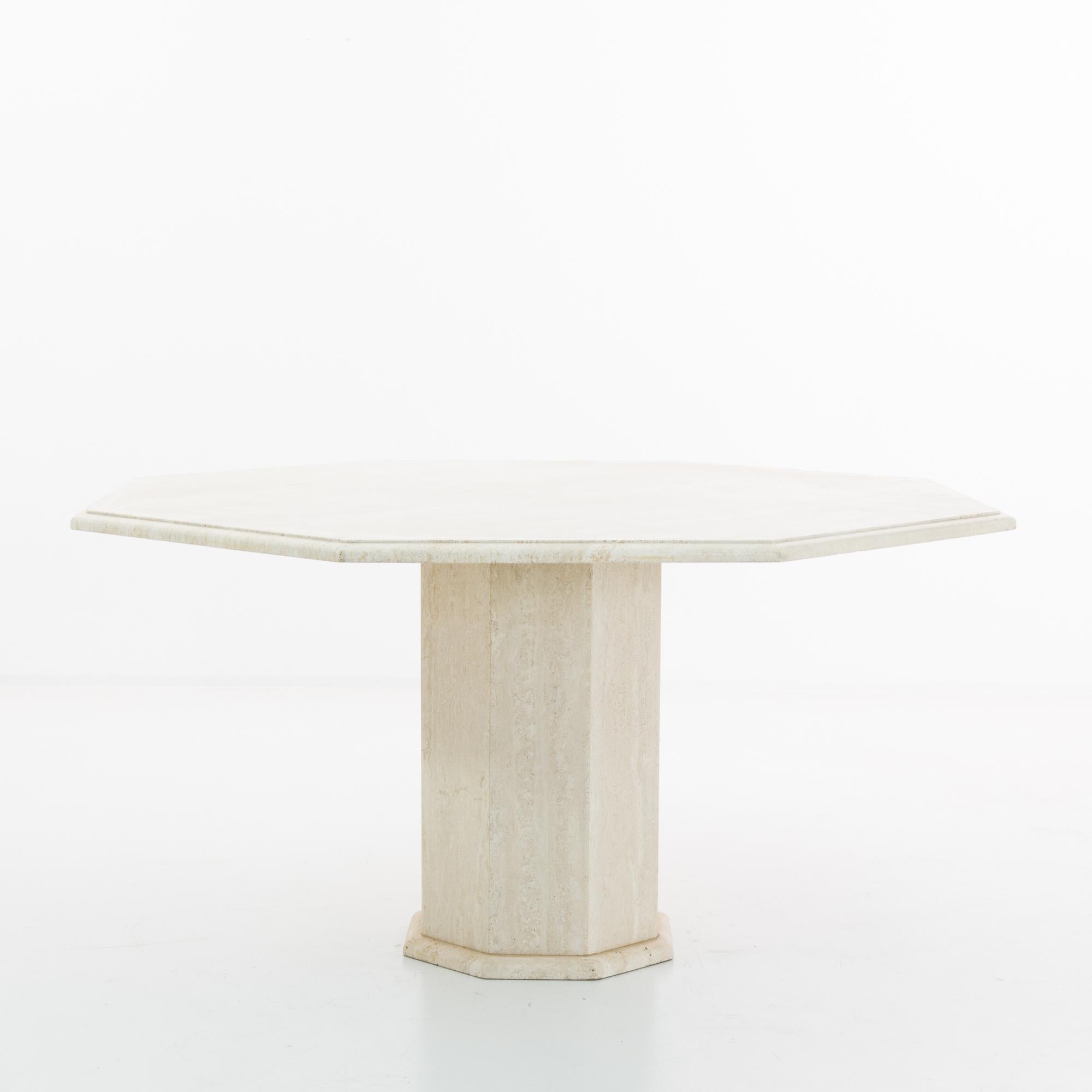 This travertine dining table was made in Italy, circa 1970. Graphic and minimalist, the classical sensibility of travertine lends a monumental quality to the modern silhouette. A ogee edged octagonal tabletop sits atop a faceted column of stone; the