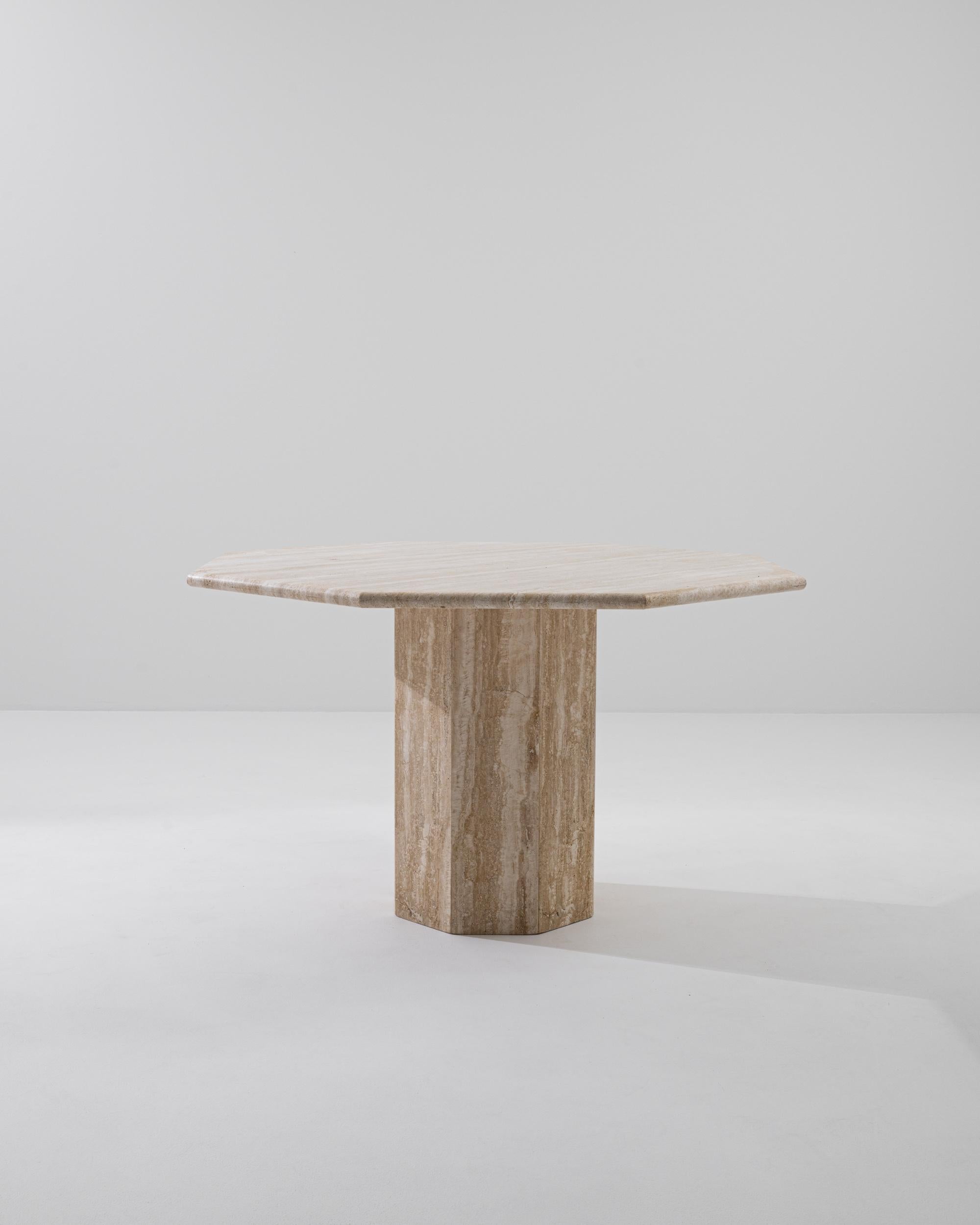 Geometric and bold, this Mid-Century Modern travertine table offers a show-stopping centerpiece. Built in Italy in the 1970s, an octagonal tabletop sits atop an eight-sided pillar, forming an angular yet harmonious silhouette. The austere beauty of
