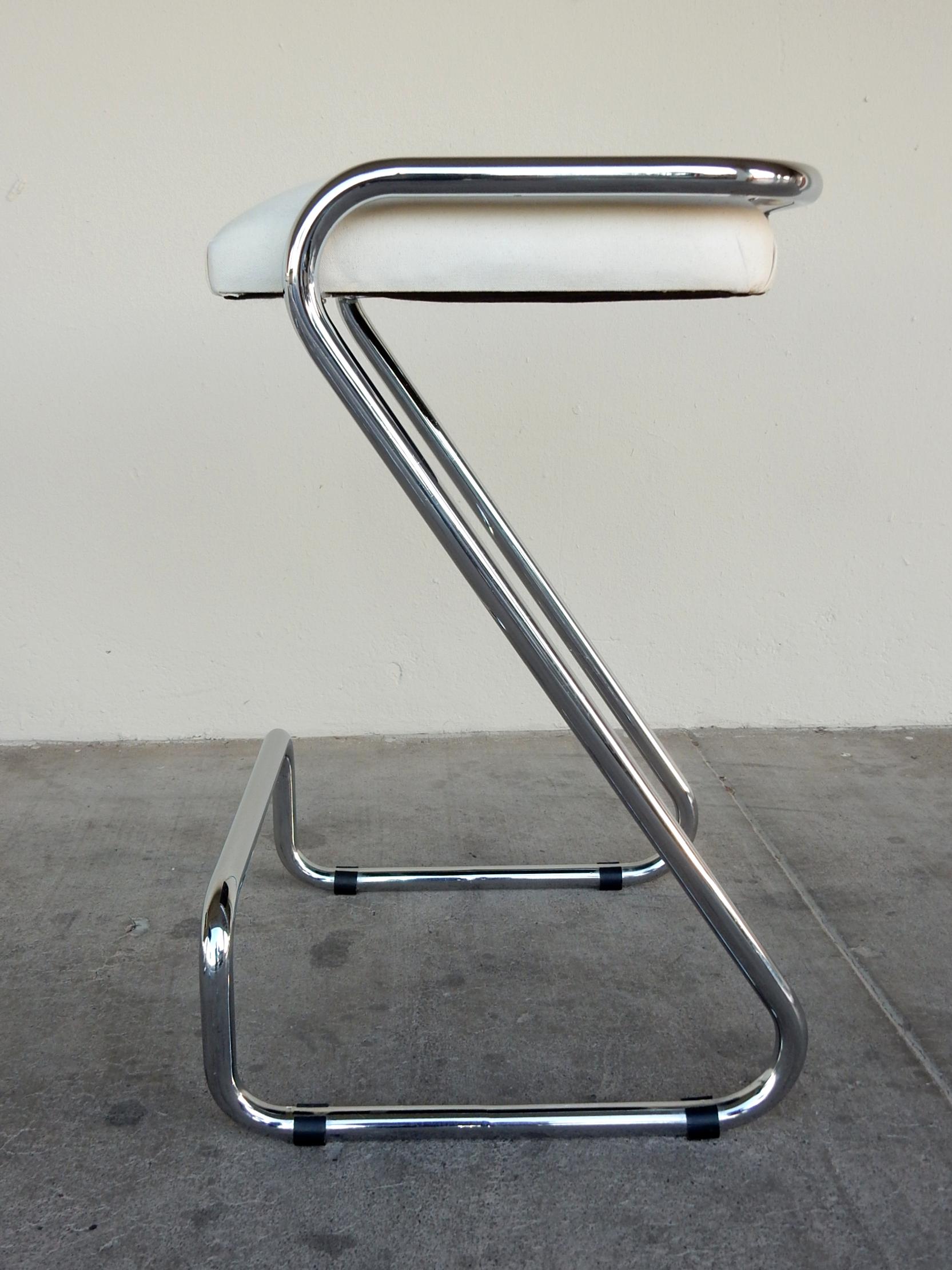 In the style of Charlotte Perriand, a set of 3 Minimalist chromed steel tube bar stools.
Z form with elevated footrest rail. White cotton fabric upholstered seating.
Signed 