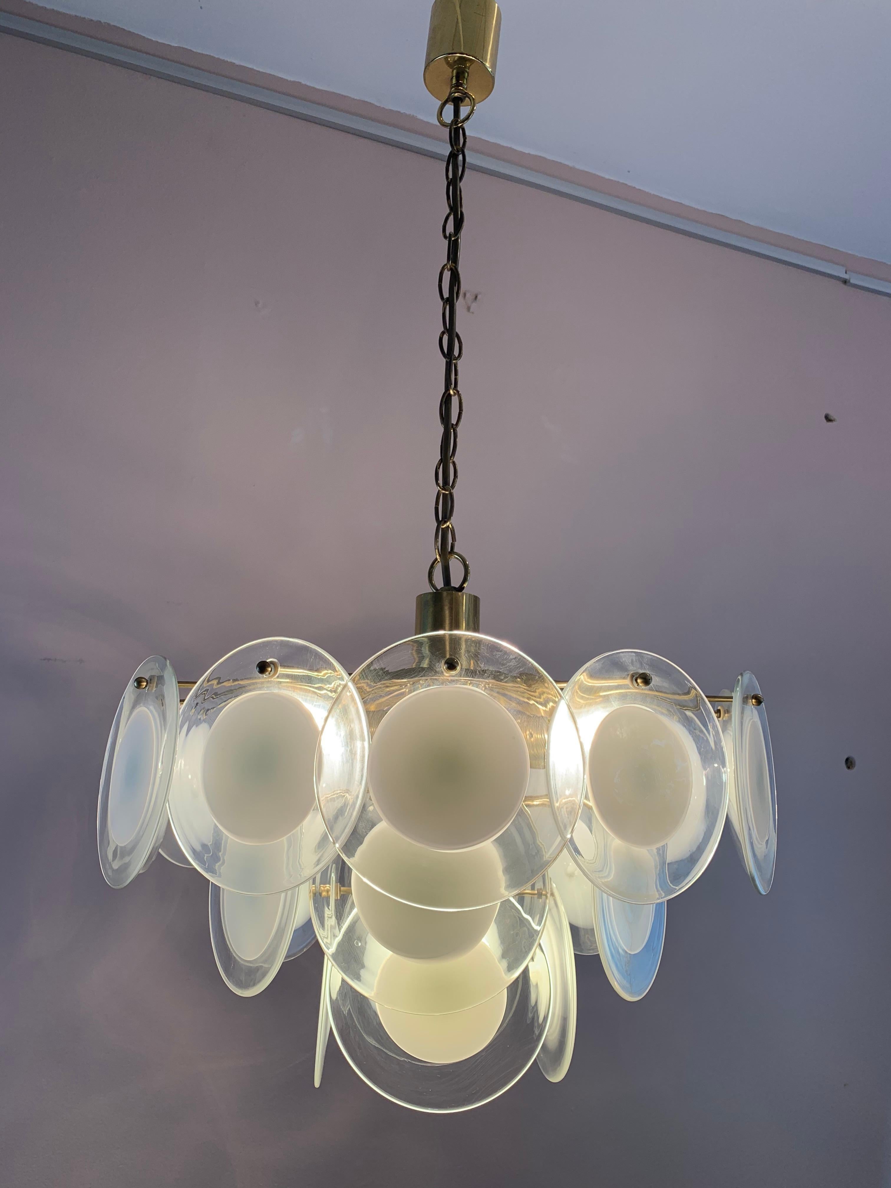 1970s Italian three-tier hanging ceiling light or chandelier in the style of Vistosi. The hand blown clear glass circular discs with white centres are suspended from a brass frame and held in place with small screws through a hole in the top of the