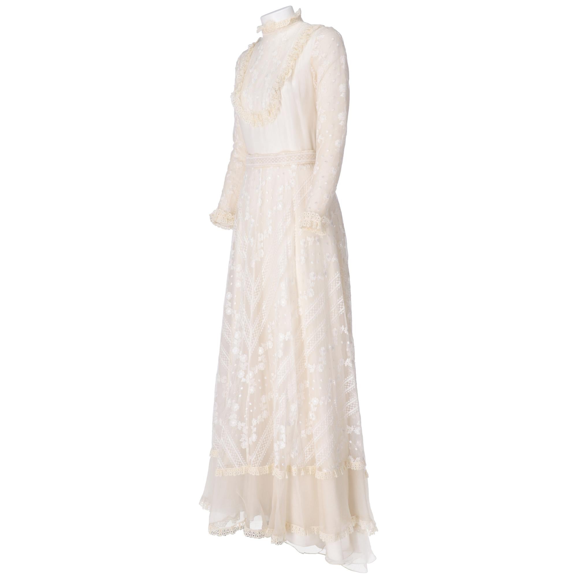 Ivory tailored wedding dress with train, cut at the waist, long layered skirt with white floral embroidery, mock neck in lace, long sleeves with lace on the hem, embroidered band at the waist, zip closure and hooks on the back.

The item has slight