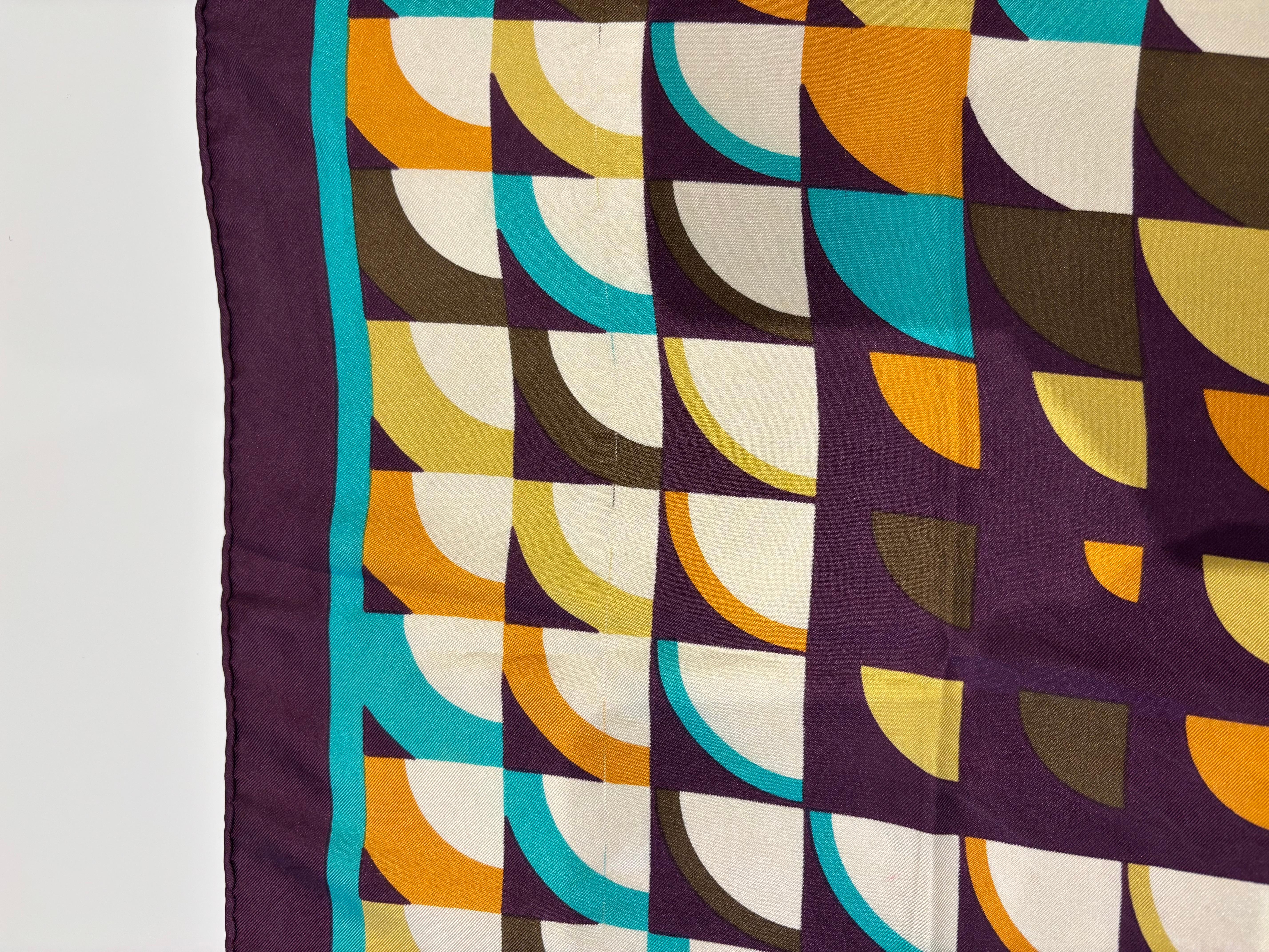 Ce design est typique des années 1970  Il est très coloré et son design est abstrait.
Le bourgogne est la couleur majoritaire, accompagné du jaune, de l'orange, du marron et du blanc.
Ce foulard en soie est en très bon état vintage à l'exception