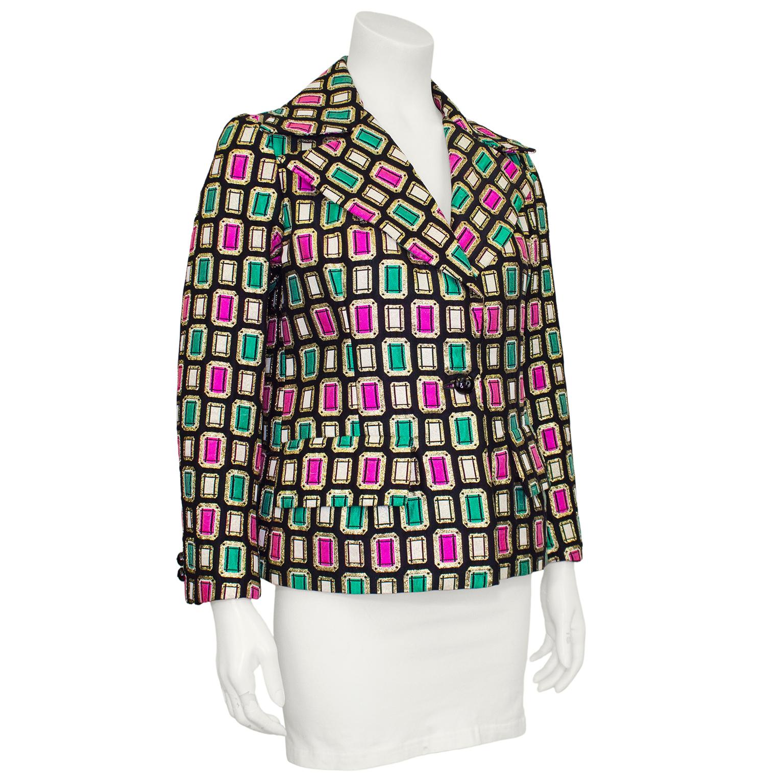 Lovely Jaeger brocade jacket from the 1970s. Black with contrasting gold, white, green and pink emerald cut graphic jewel pattern. Notched collar, single button, bracelet length sleeves and flap pockets at hips. Back side seams feature a panel of