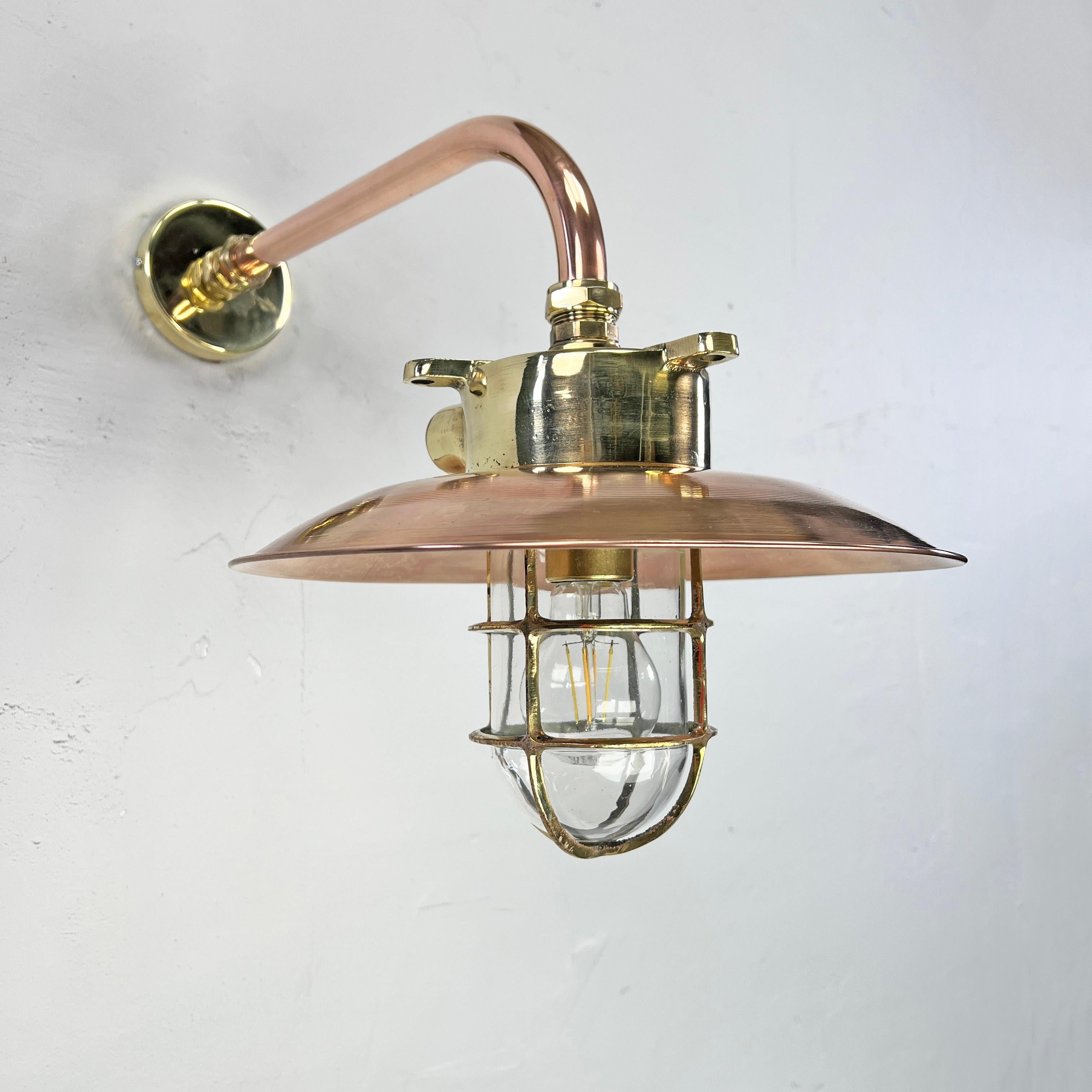 An industrial brass explosion proof wall light fixture with a bespoke brass and copper cantilever arm.

The lamp was originally made in Japan which was reclaimed from decommissioned cargo ships made during the 1970s. 

This fixture has been