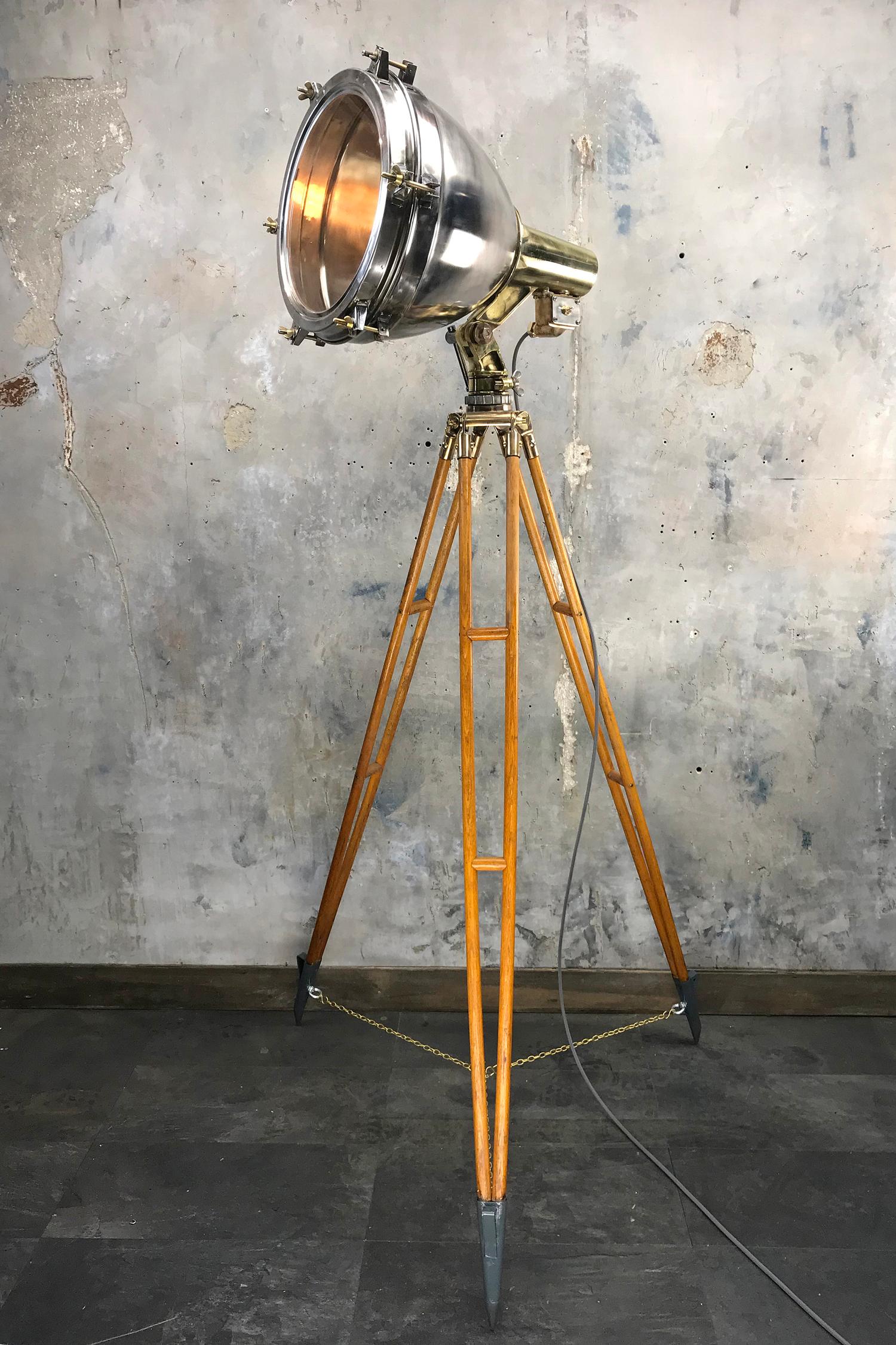 A statuesque vintage industrial floor lamp. The stainless steel and brass searchlight has been paired with a timber and bronze tripod to create a bespoke tall floor lamp 

Specifications: 
Width of Lamp: 52cm
Depth of Lamp: 60cm
Height: