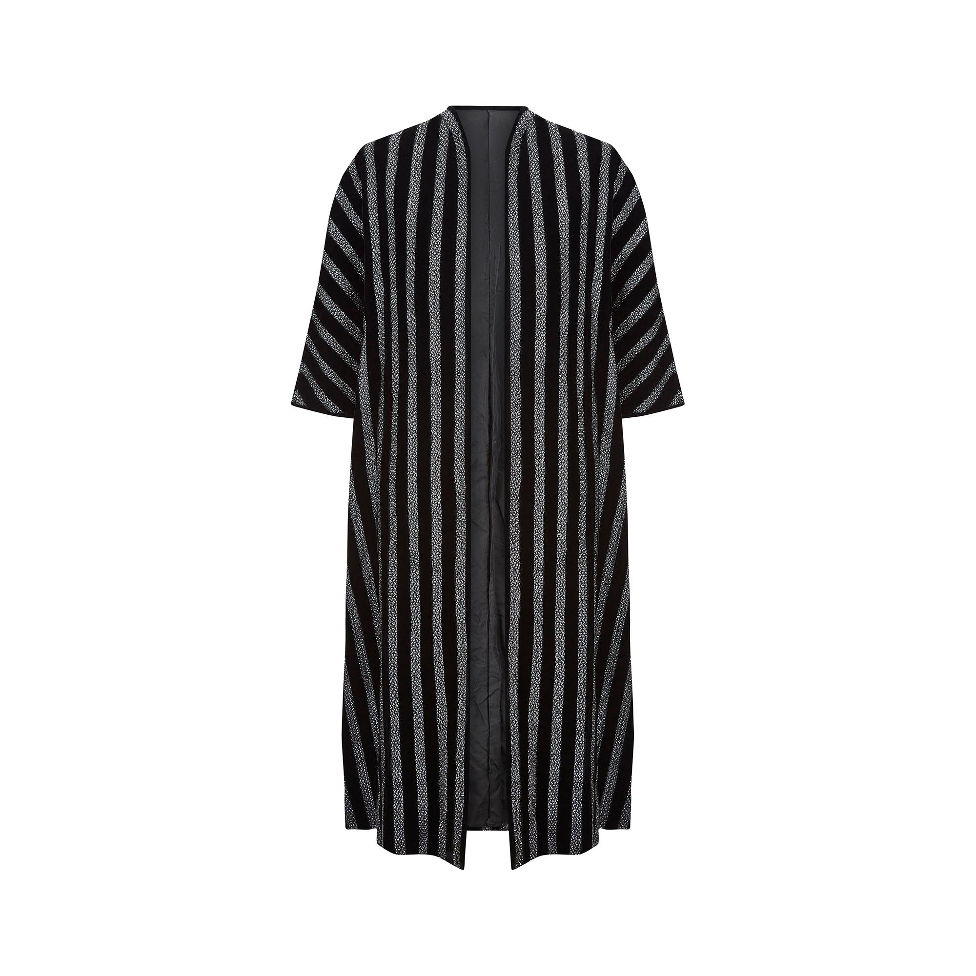 A show-stopper of a jacket, this late 1960s to early 1970s duster coat is the perfect throw-on finish to your party look. A substantial, weighty piece of tailoring, it has been created from thick 100% cotton black velvet woven with stripes of
