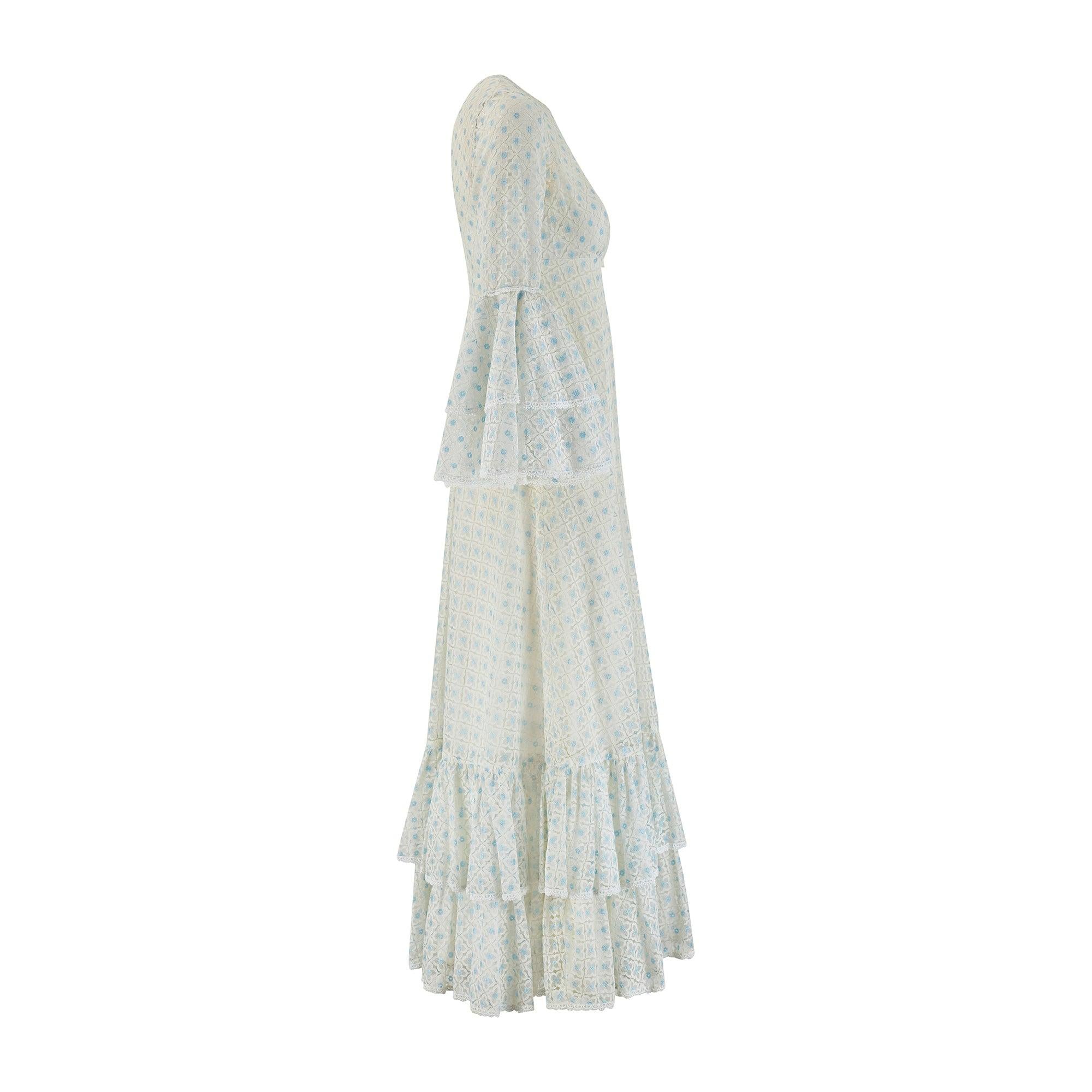 Este maxivestido de encaje de principios de los años 70 fue confeccionado por la marca británica Jean Varon y es un bello ejemplo de la inclinación del diseñador por los detalles románticos, sinónimo de su trabajo durante esta época. El vestido está