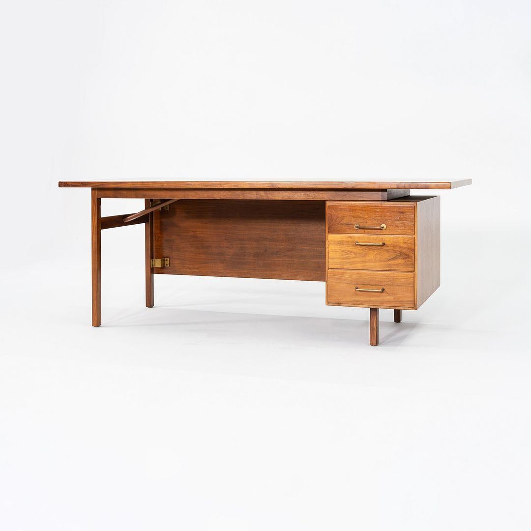 Il s'agit d'un bureau de direction en noyer, conçu par Jens Risom dans les années 1960. Produit par Risom Design/One, cet exemple date des années 1970. Il comporte plusieurs tiroirs qui offrent un grand espace de rangement, et offre un espace de